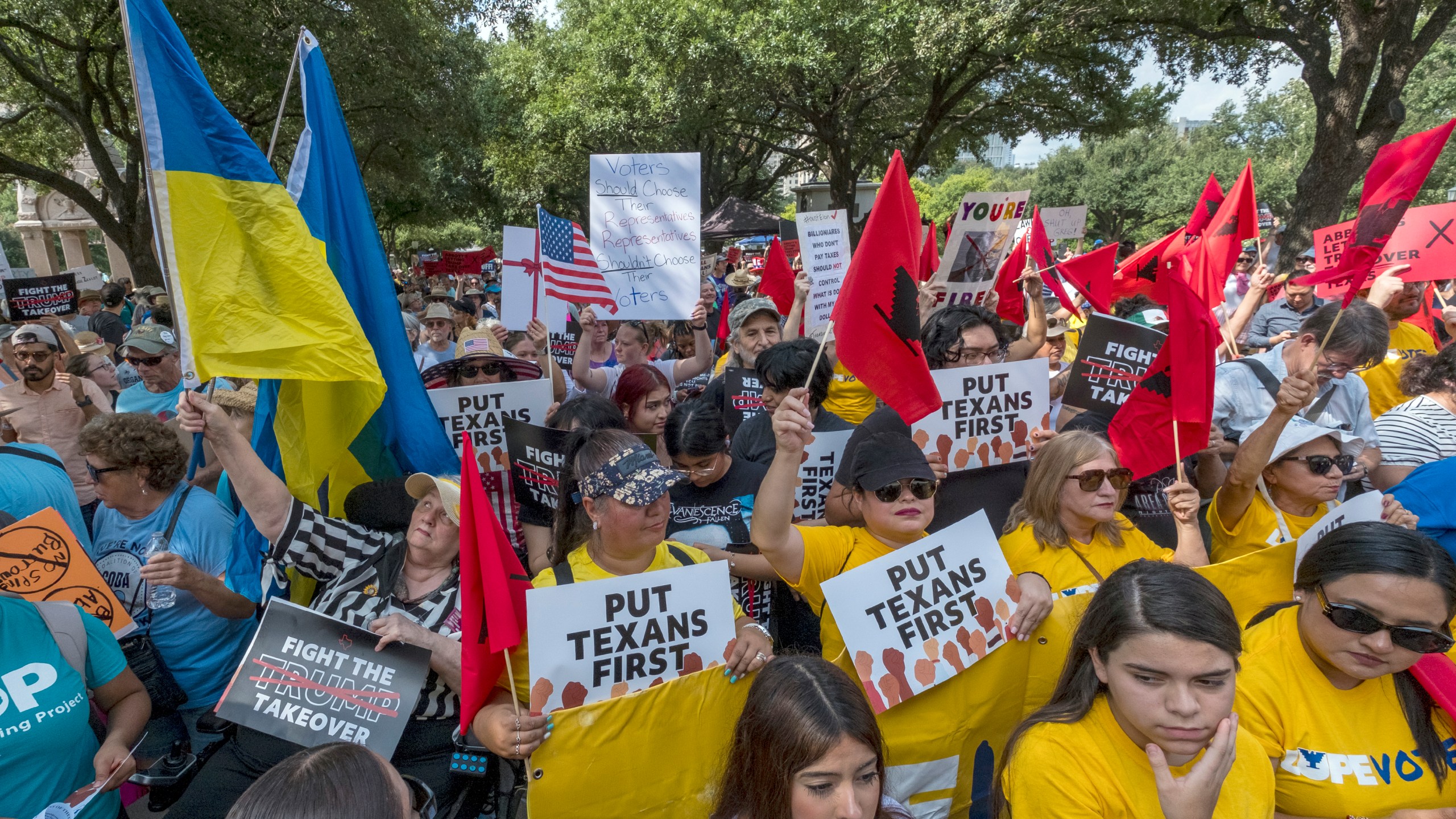 Supporters gather in the shade during the Fight The Trump Takeover Rally held at the State Capitol, Saturday, Aug. 16, 2025, in Austin, Texas, to protest congressional redistricting efforts by Texas Republicans and President Donald Trump. (AP Photo/Rodolfo Gonzalez)
