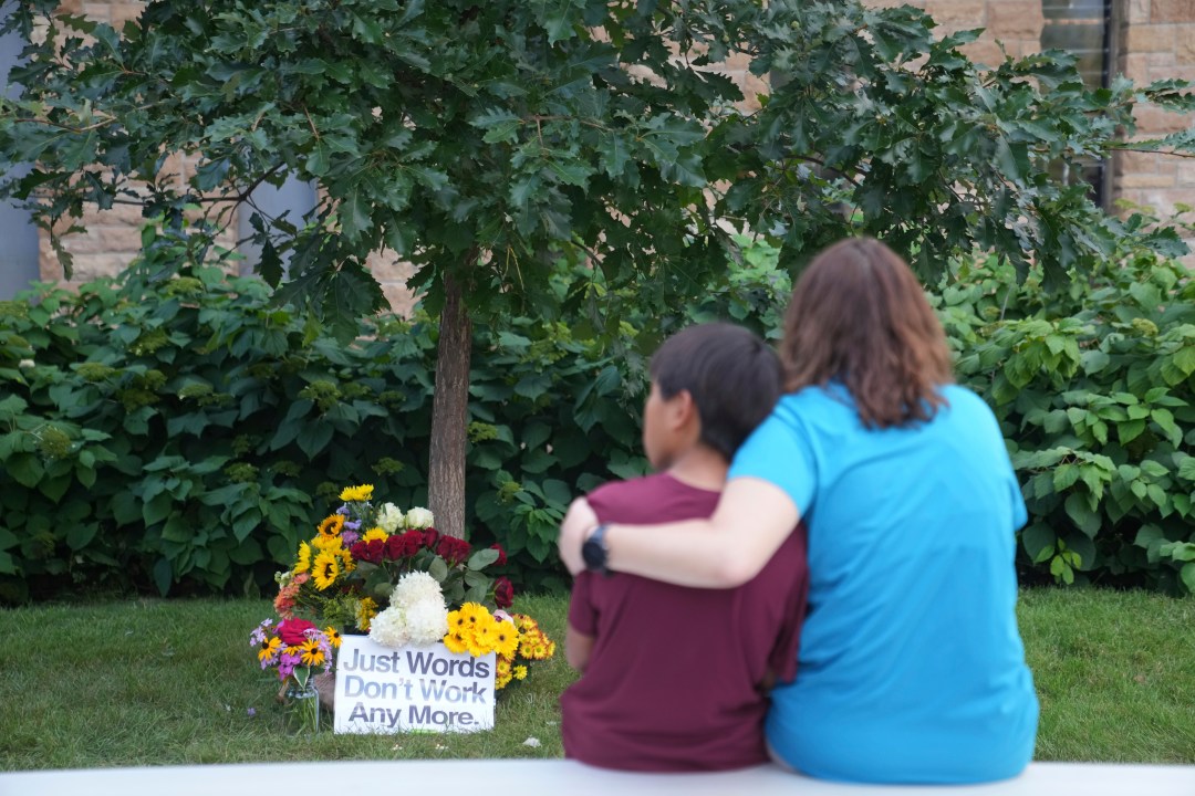 An adult and a child embrace outside Annunciation Catholic Church