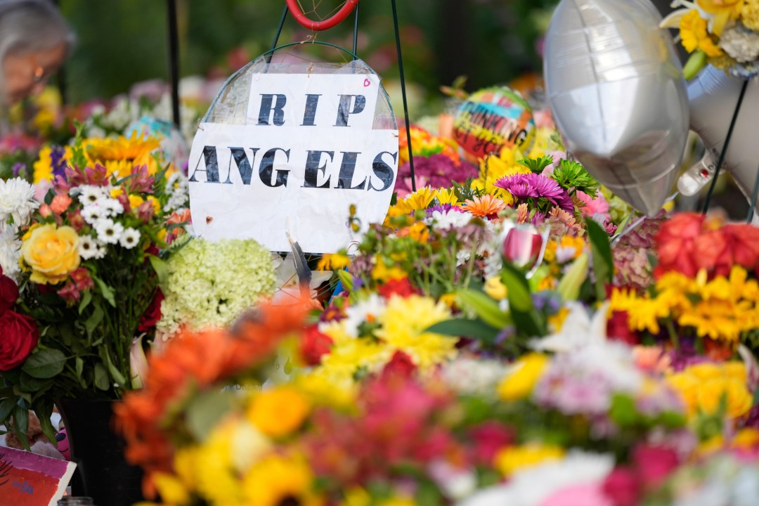 A sign reading "RIP Angels" sits amid flowers at a memorial at Annunciation Catholic Church