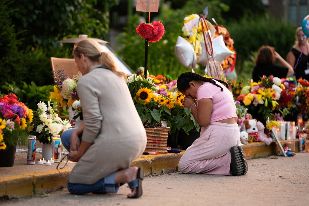 Two people kneel before a memorial at Annunciation Catholic Church