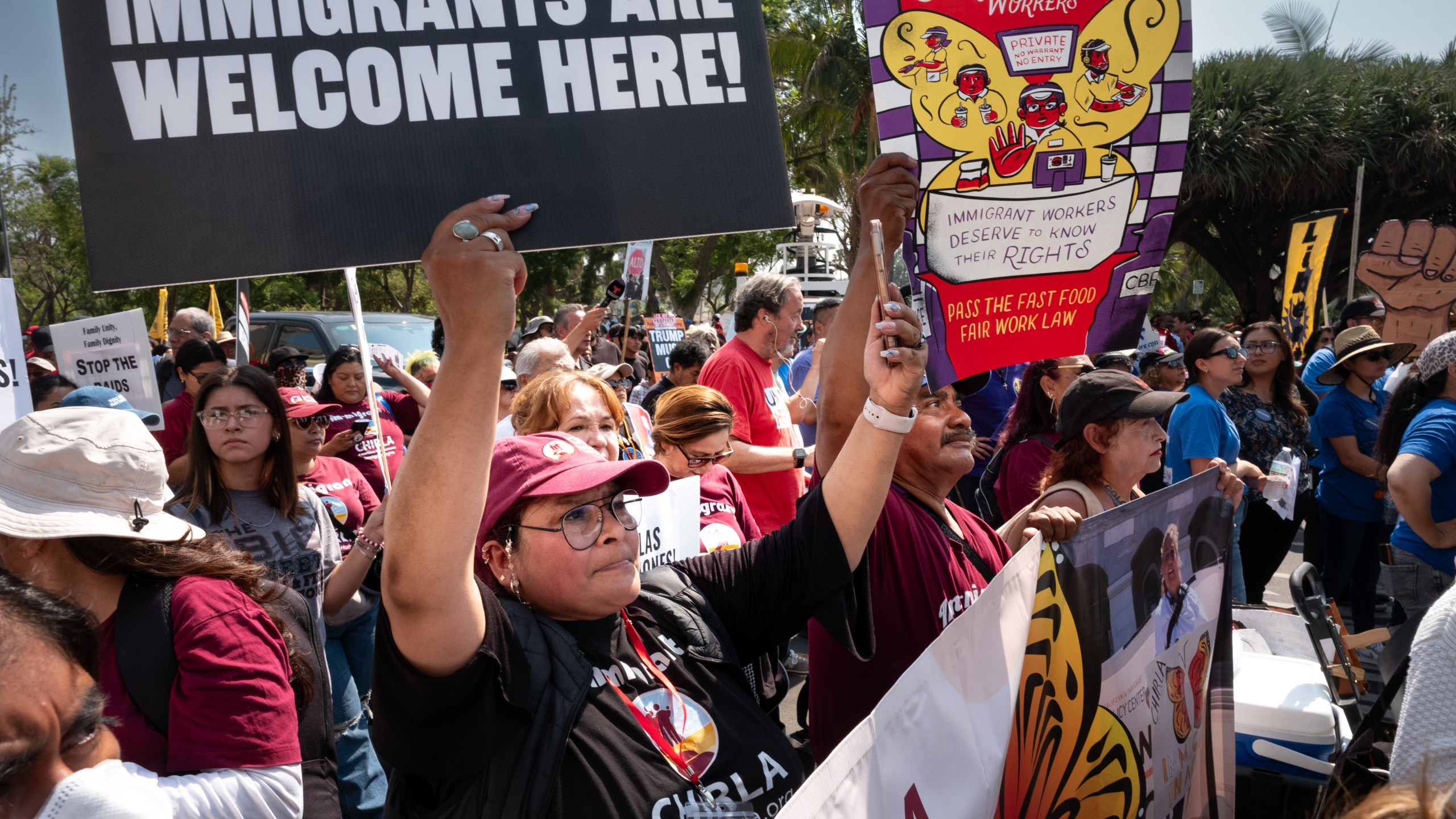 Protesters at a rally hold signs reading IMMIGRANTS ARE WELCOME HERE