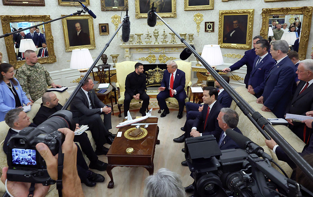 President Donald Trump meets with Ukrainian President Volodymyr Zelensky in the Oval Office surrounded by staffers and cameras