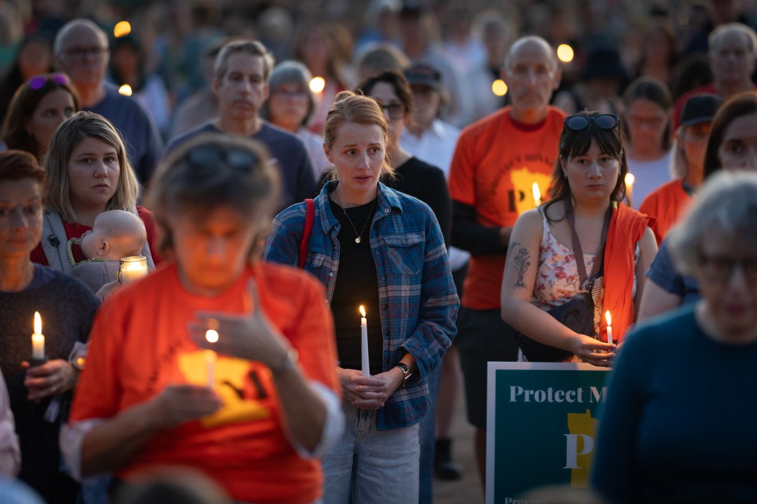 People hold candles at a vigil for Annunciation Catholic School shooting victims