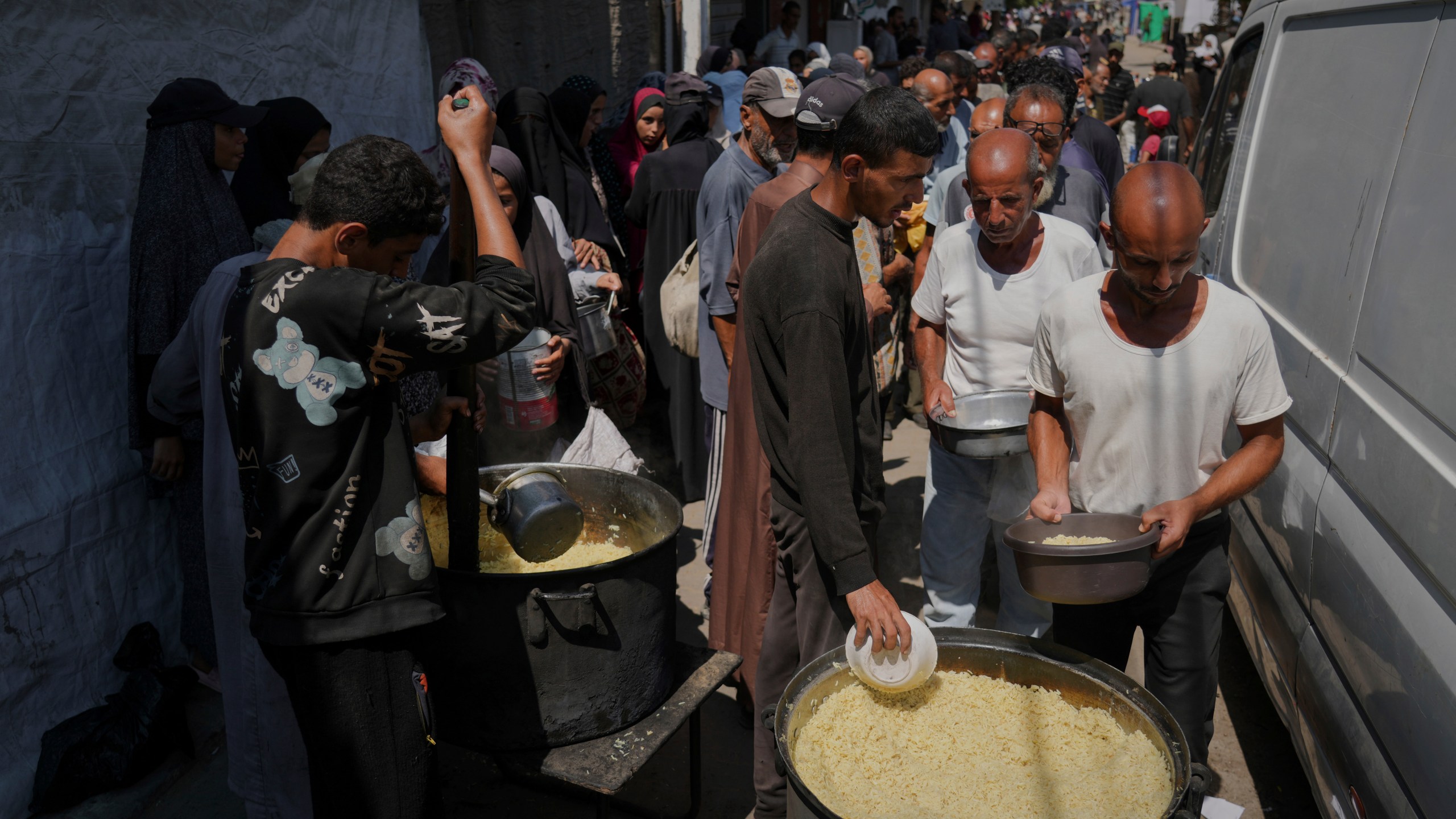 Palestinians line up to receive donated food at a community kitchen in Deir al-Balah, southern Gaza Strip, Saturday, Sept. 6, 2025. (AP Photo/Jehad Alshrafi)