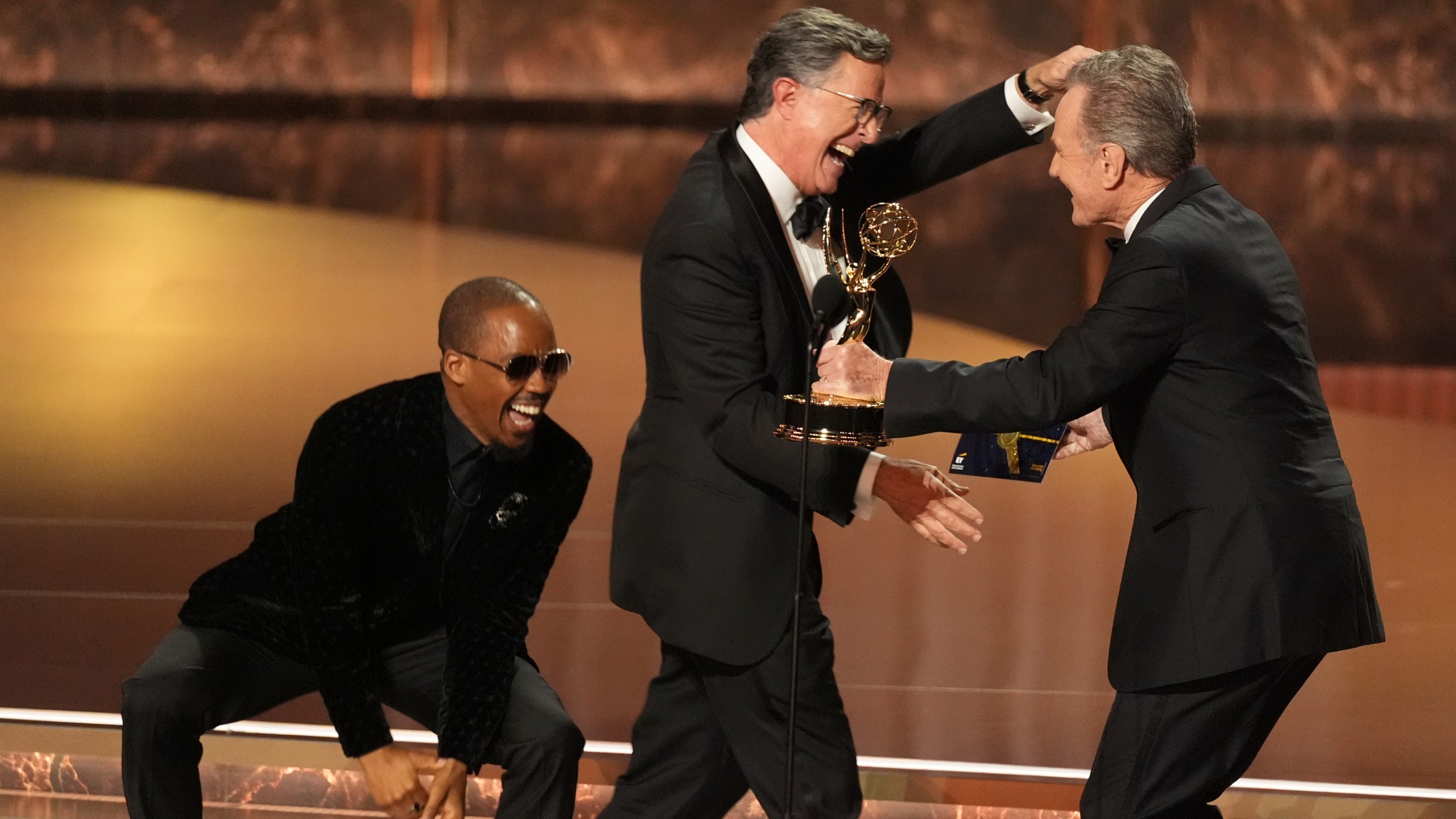 Bryan Cranston, right, presents the award for outstanding talk series to Stephen Colbert, left, for "The Late Show with Stephen Colbert" during the 77th Primetime Emmy Awards on Sunday, Sept. 14, 2025, at the Peacock Theater in Los Angeles. (AP Photo/Chris Pizzello)