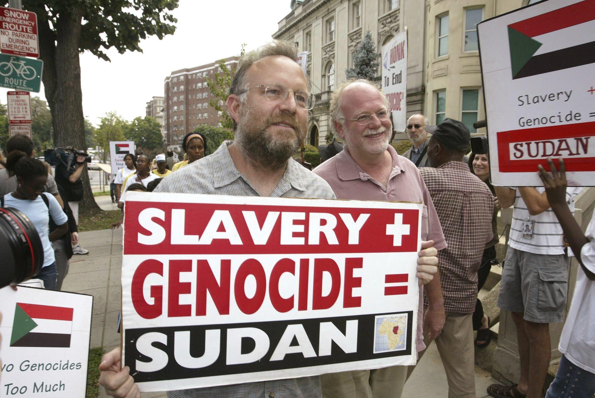 FILE - Founders of Ben & Jerry's Ice Cream Jerry Greenfield , left, and Ben Cohen, pink shirt, protest in front of Sudan's embassy July 29, 2004, in Washington. (AP Photo/Charles Dharapak, File)