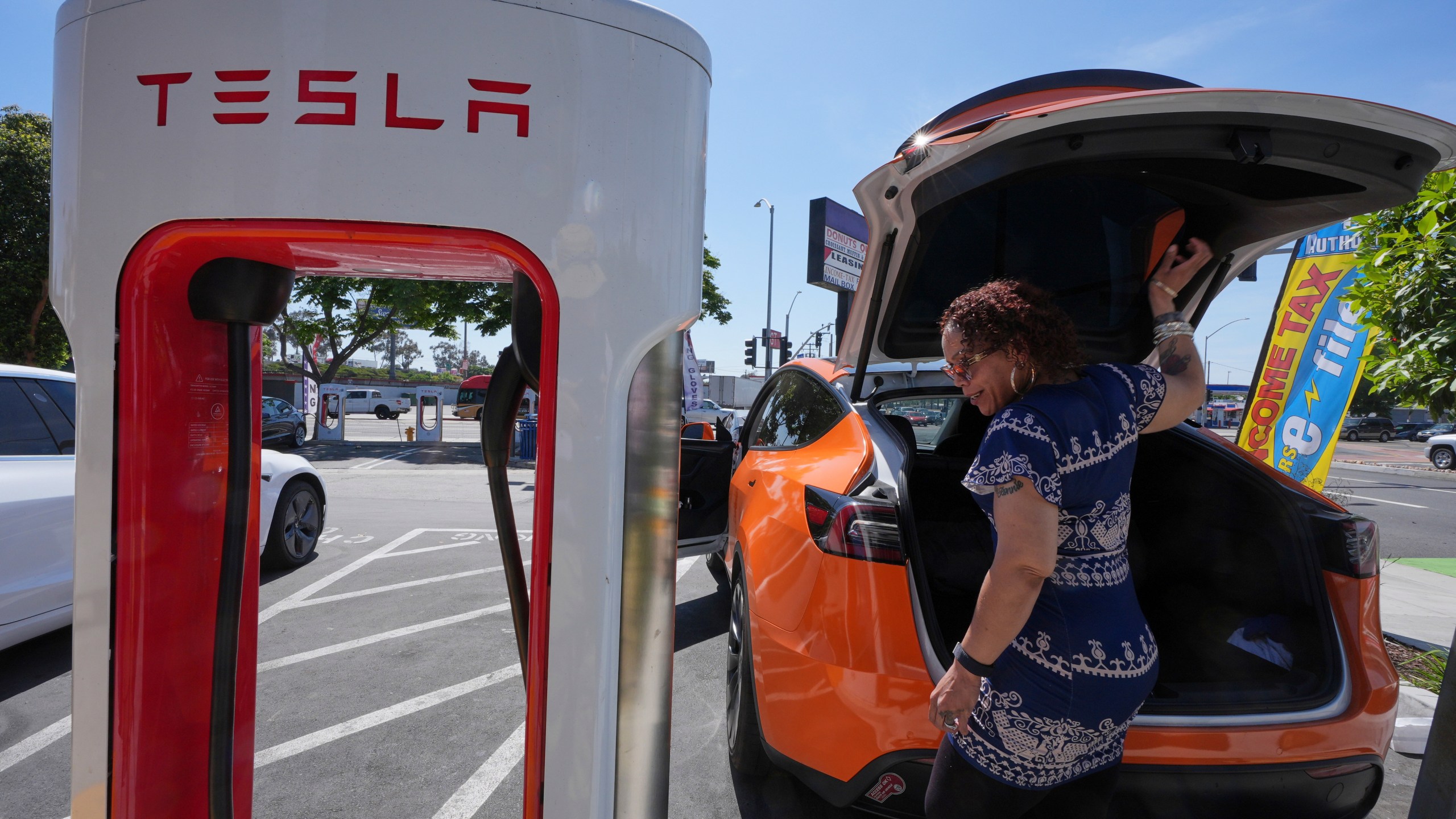 FILE - Janelle Lowe prepares to charge her electric vehicle at a station May 22, 2025, in Long Beach, Calif. (AP Photo/Damian Dovarganes, File)
