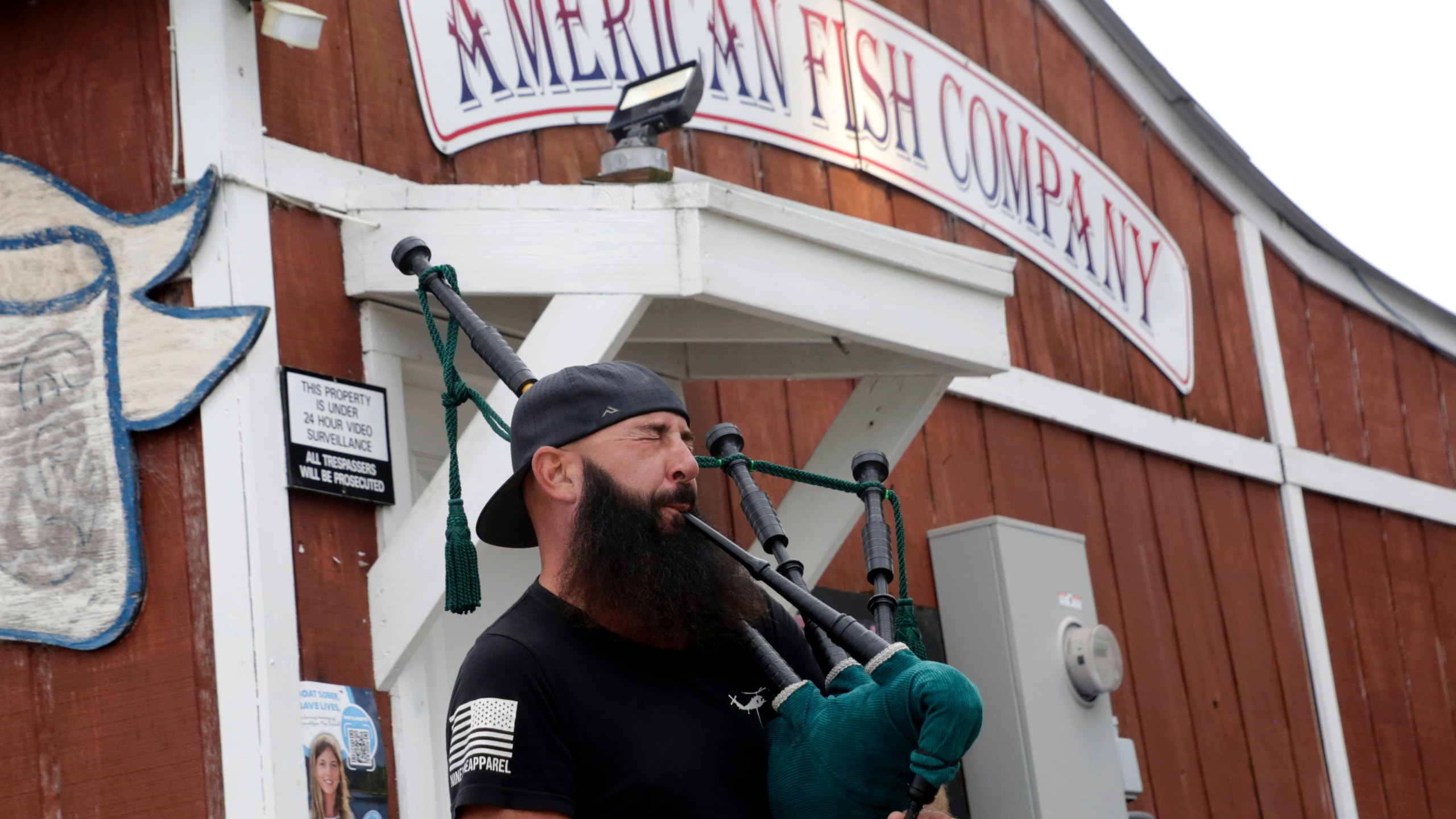 Joey Whitaker from Holden Beach plays "Amazing Grace" on the bagpipes in front of the American Fish Company following a fatal shooting that occurred here the night before, Sunday, Sept. 28, 2025, in Southport, N.C. (AP Photo/Chris Seward)