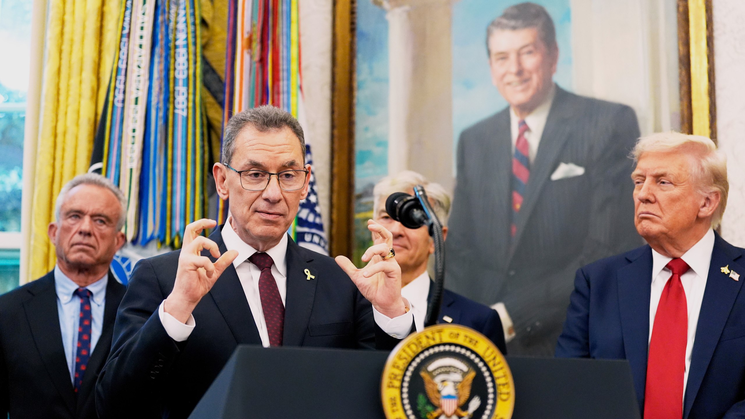 Albert Bourla, chairman and chief executive officer of the pharmaceutical company Pfizer. speaks in the Oval Office of the White House, Tuesday, Sept. 30, 2025, in Washington, as from left, Secretary of Health and Human Services Robert F. Kennedy, Jr., Mehmet Oz, Administrator for the Centers for Medicare & Medicaid Services and President Donald Trump, right, look on. (AP Photo/Alex Brandon)