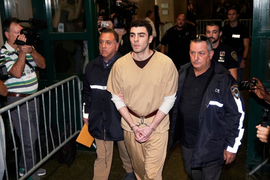 Luigi Mangione, wearing a beige jumpsuit and handcuffs, is escorted into court
