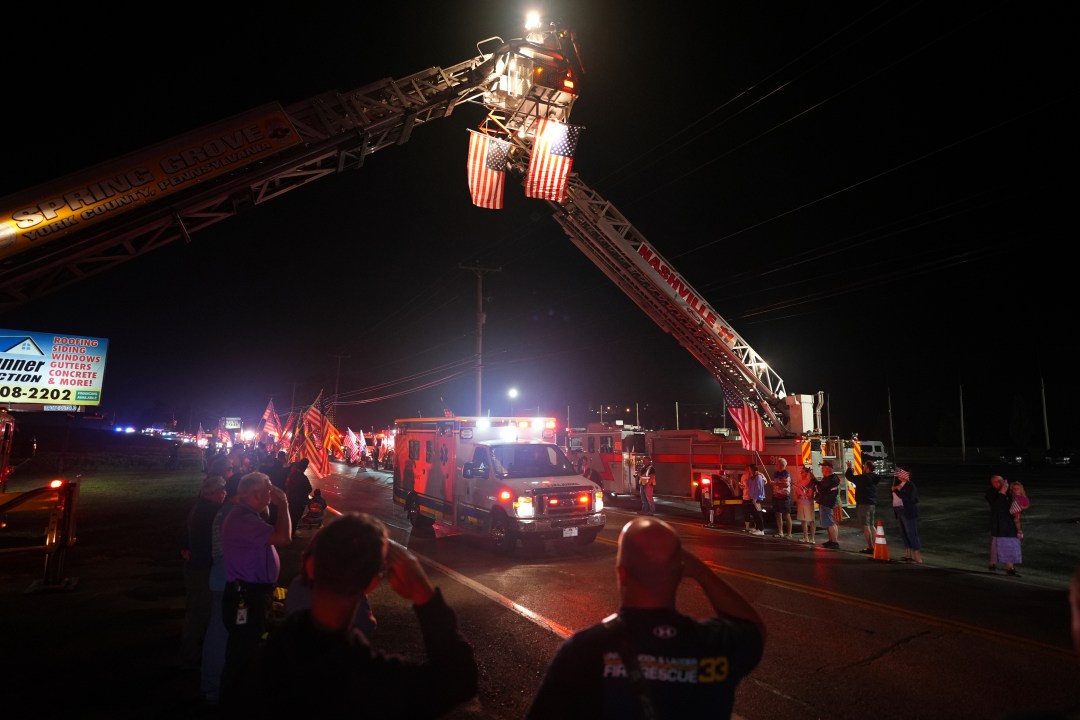 Attendees watch a procession after multiple police officers were shot and killed