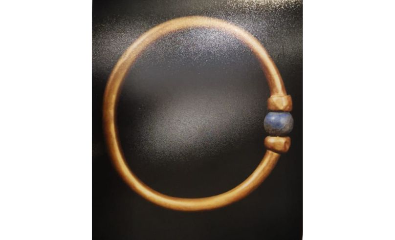 A gold bracelet with a blue bead on it