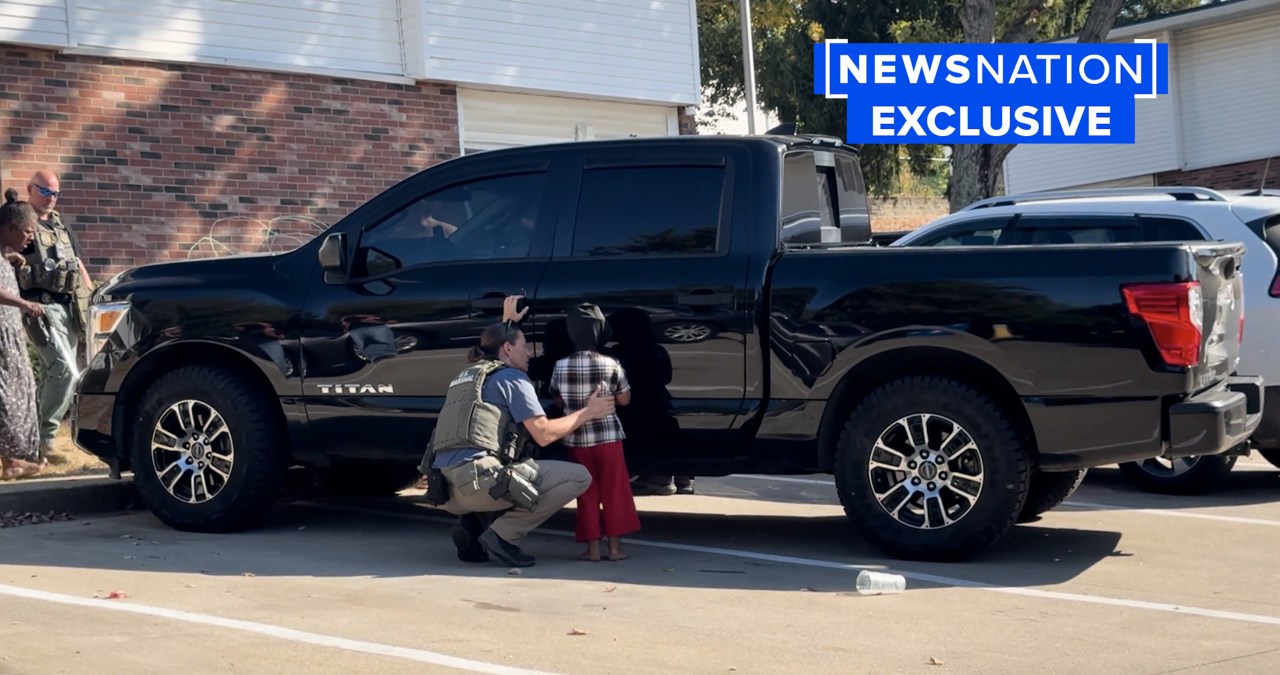 A U.S. Marshal bends down to talk to a child