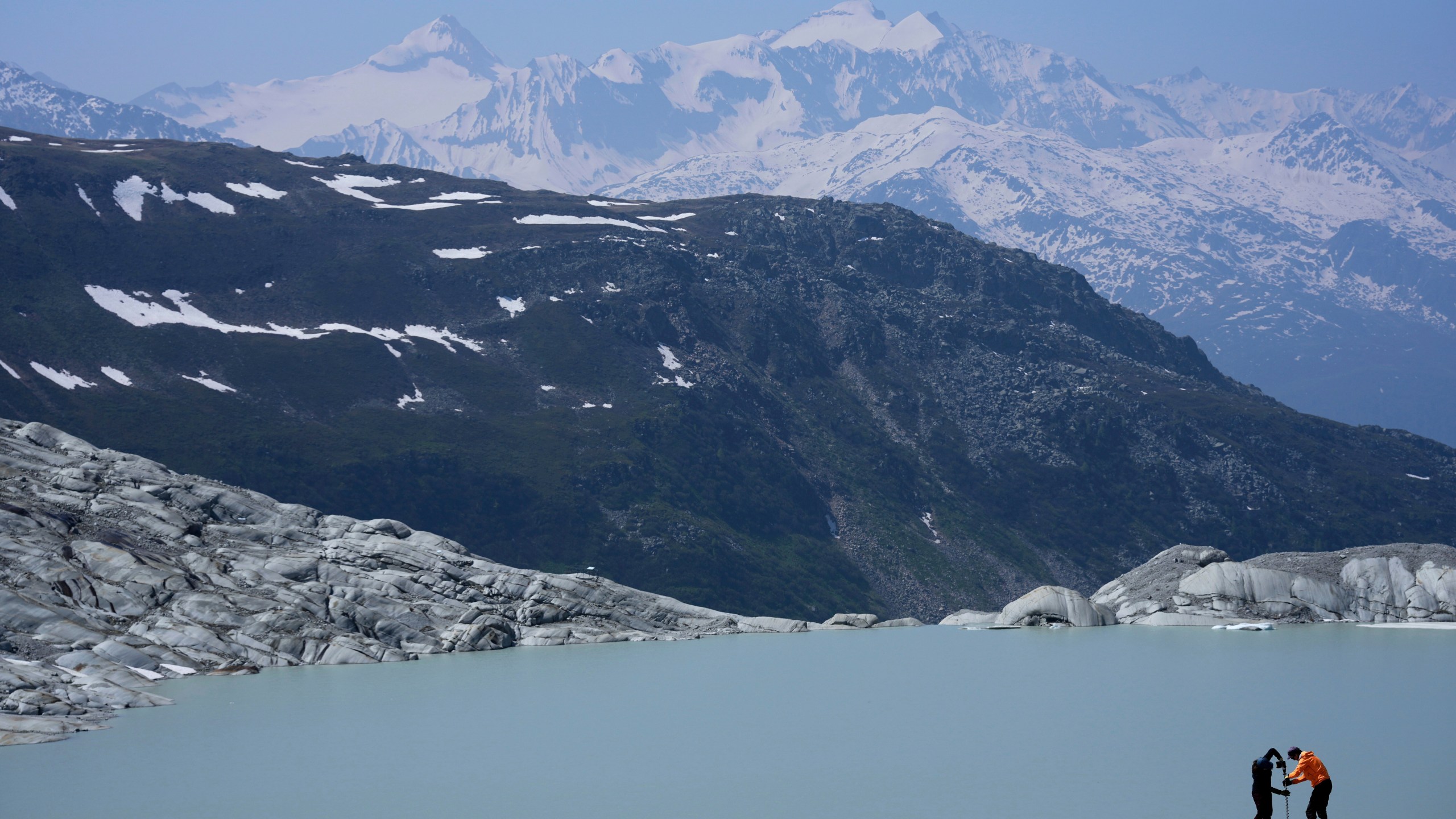 FILE - Matthias Huss, of the Federal Institute of Technology in Zurich and glacier monitoring group GLAMOS, and Monica Ursina Jaeger prepare a camera at the Rhone Glacier near Goms, Switzerland, on June 10, 2025. (AP Photo/Matthias Schrader, File)