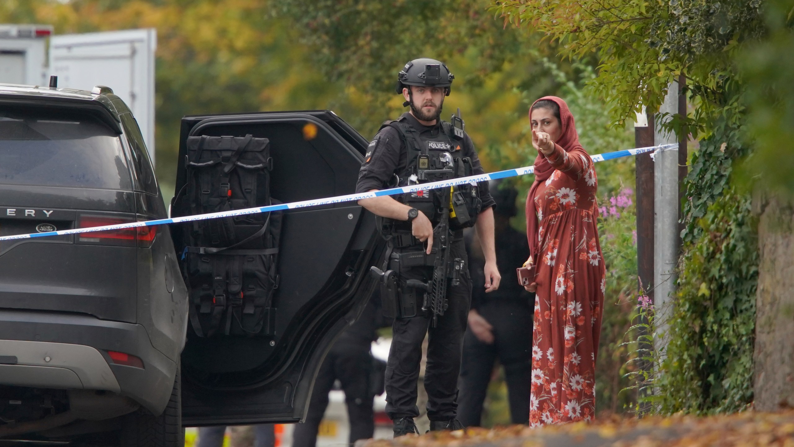 An armed police officer speaks to member of the public near the scene of a stabbing incident at Heaton Park Hebrew Congregation synagogue, in Crumpsall, Manchester, England, Thursday, Oct. 2, 2025. (AP Photo/Ian Hodgson)
