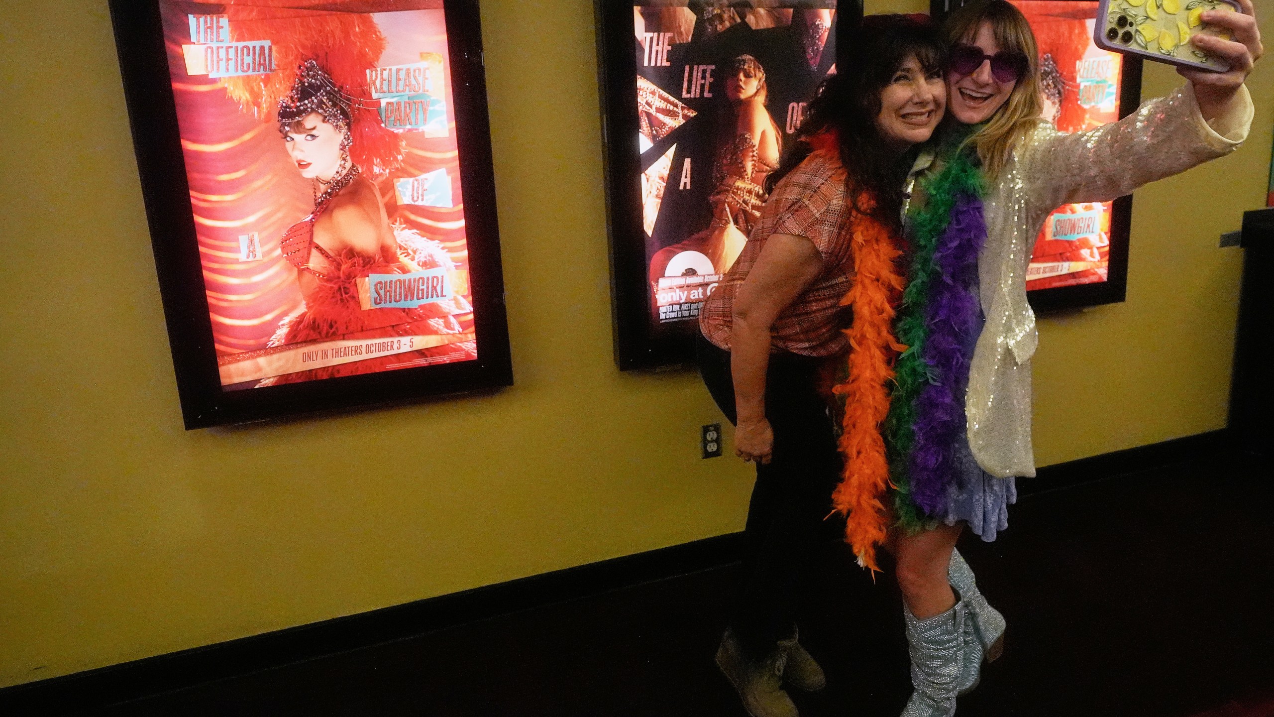 Amy Davis, left, and Jenni Boyer take photos before the official release of Taylor Swift's new album, "The Life of a Showgirl," at the AMC Metreon in San Francisco, Friday, Oct. 3, 2025. (AP Photo/Jeff Chiu)
