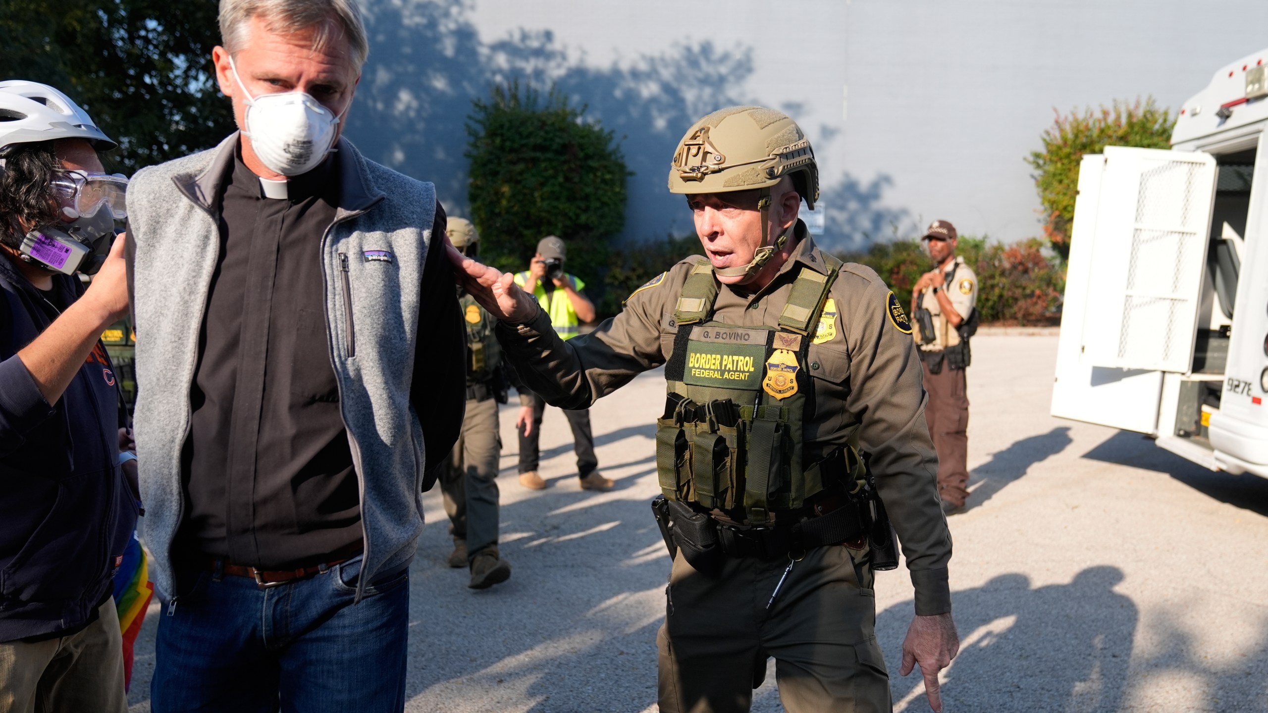 Gregory Bovino walks along a protester with his hands behind his back