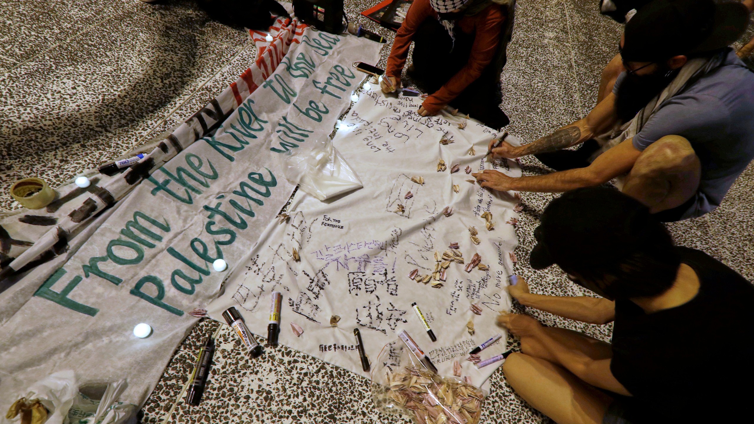 Pro-Palestinian protesters sign and make paper cranes during a candlelight vigil in support of Palestinians, in Taipei, Taiwan, Tuesday, Oct. 7, 2025. (AP Photo/Chiang Ying-ying)
