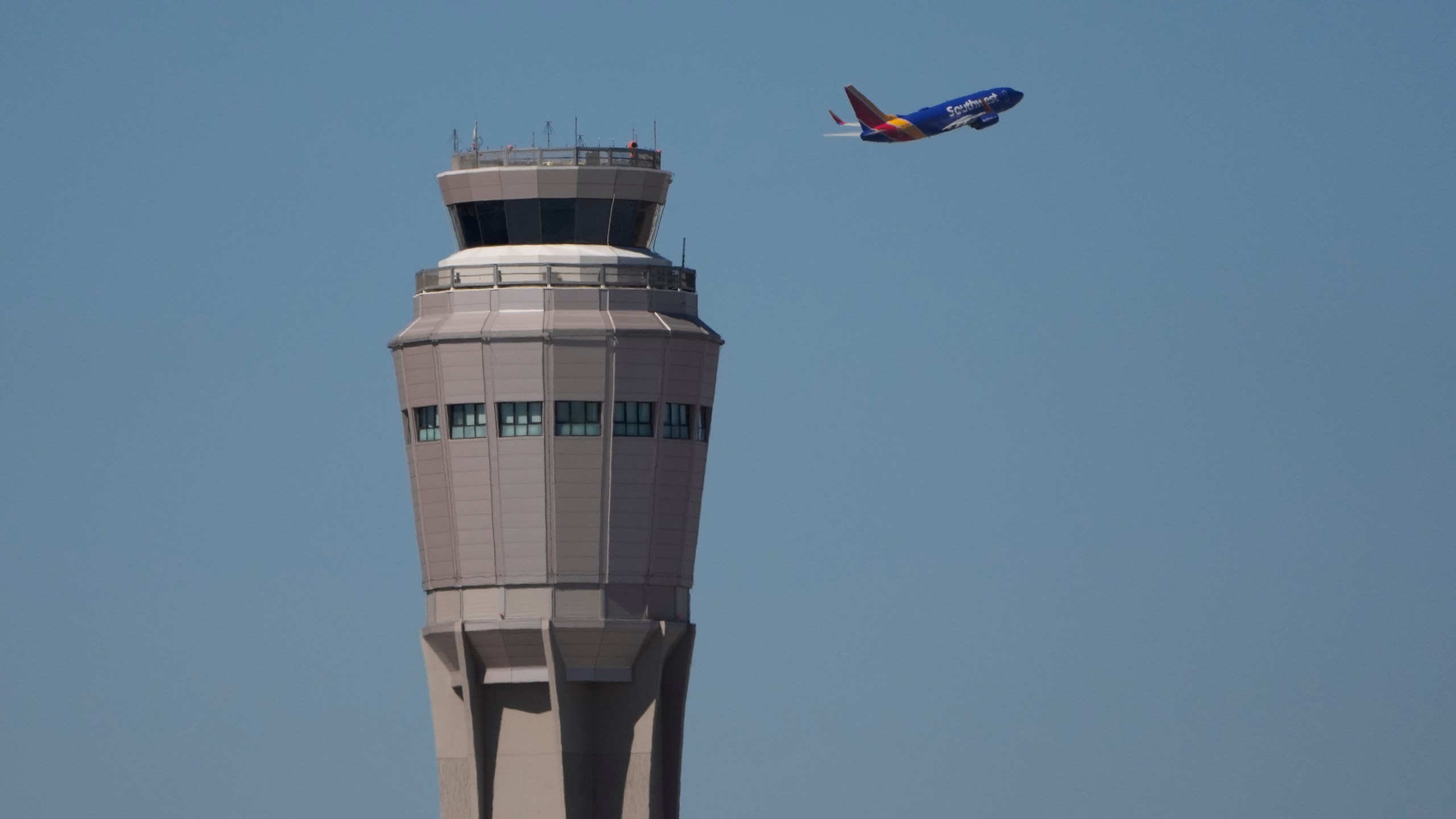 A plane takes off near the air traffic control tower at Harry Reid International Airport, Tuesday, Oct. 7, 2025, in Las Vegas. (AP Photo/John Locher)