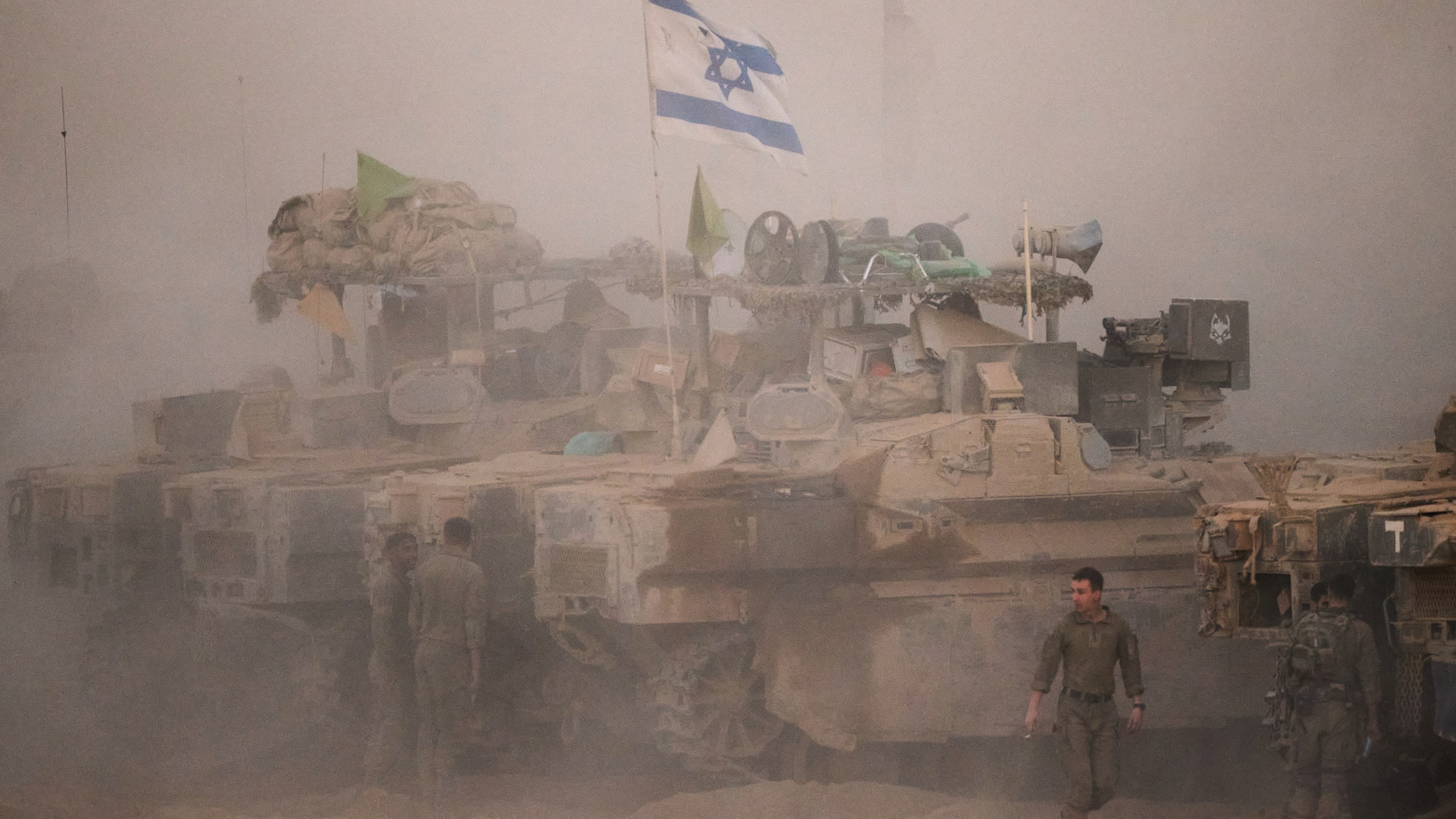 Israeli soldiers stand near their tanks along the Israeli-Gaza border, as seen from southern Israel, Friday, Oct. 10, 2025, after Israel and Hamas have agreed to a pause in their war and the release of the remaining hostages. (AP Photo/Emilio Morenatti)