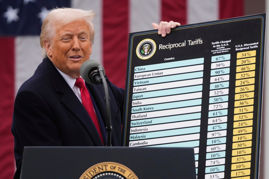 President Donald Trump speaks during an event while holding up a graphic of numbers