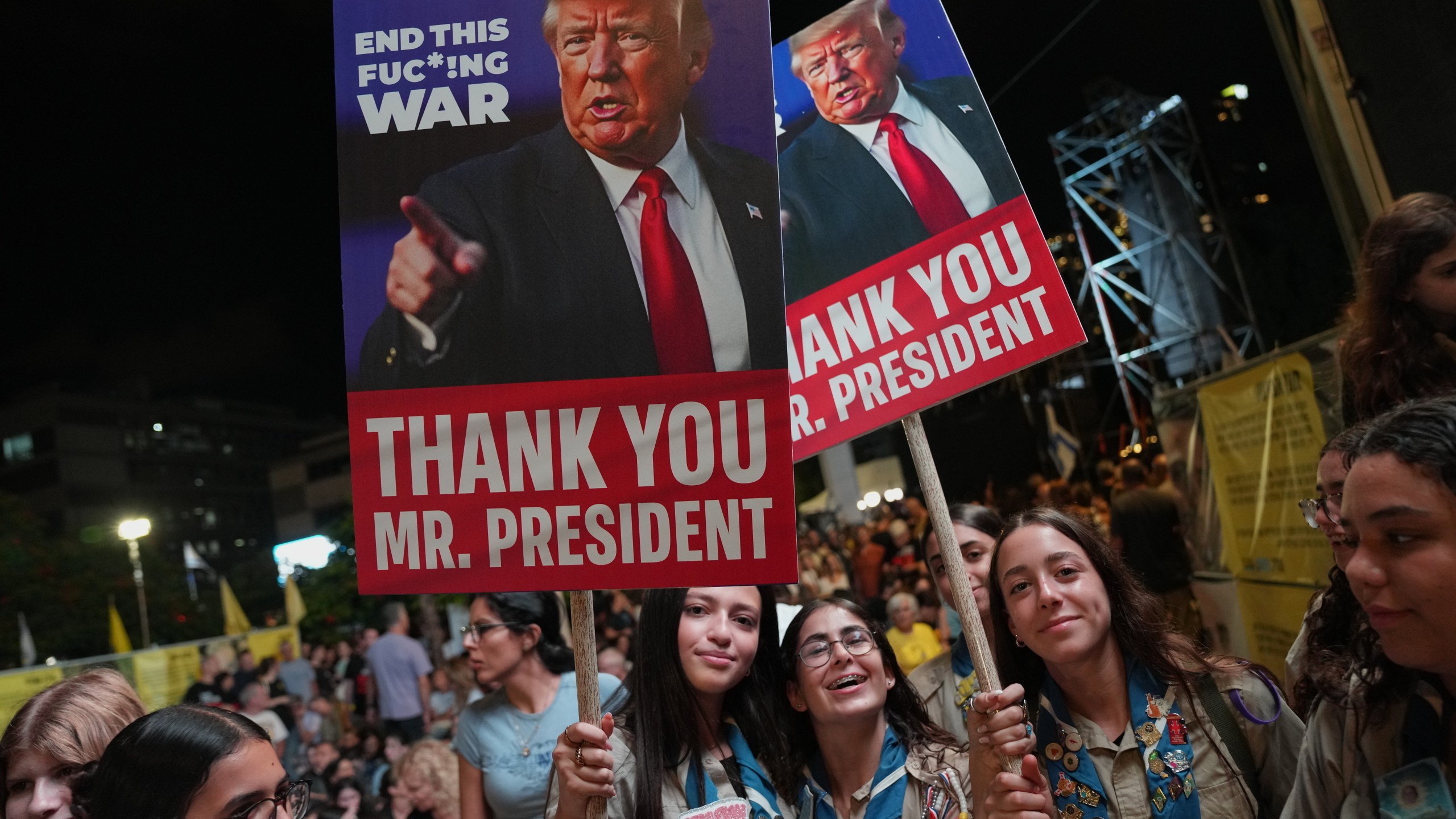 Holding up signs with images depicting the U.S. President Donald Trump people take part in a rally in support of hostages kidnapped by Hamas, at a plaza known as hostages square, in Tel Aviv, Israel, Saturday, Oct. 11, 2025, ahead of the expected release of the hostages held in the Gaza Strip. (AP Photo/Francisco Seco)