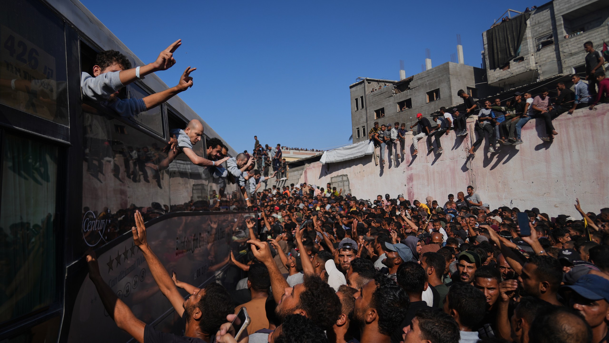 People gather to greet freed Palestinian prisoners arriving on buses in the Gaza Strip after their release from Israeli jails under a ceasefire agreement between Hamas and Israel, outside Nasser Hospital in Khan Younis, southern Gaza Strip, Monday, Oct. 13, 2025. (AP Photo/Abdel Kareem Hana)