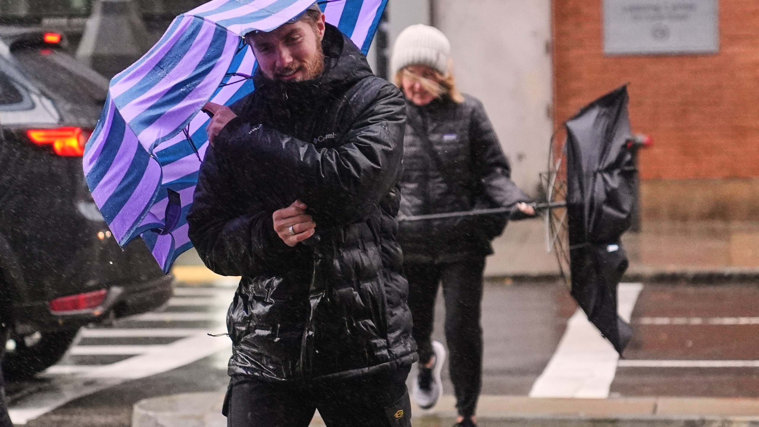 Two people battle gusts with their umbrellas as they fight a wind-driven rain storm, Monday, Oct. 13, 2025, in Boston. (AP Photo/Charles Krupa)