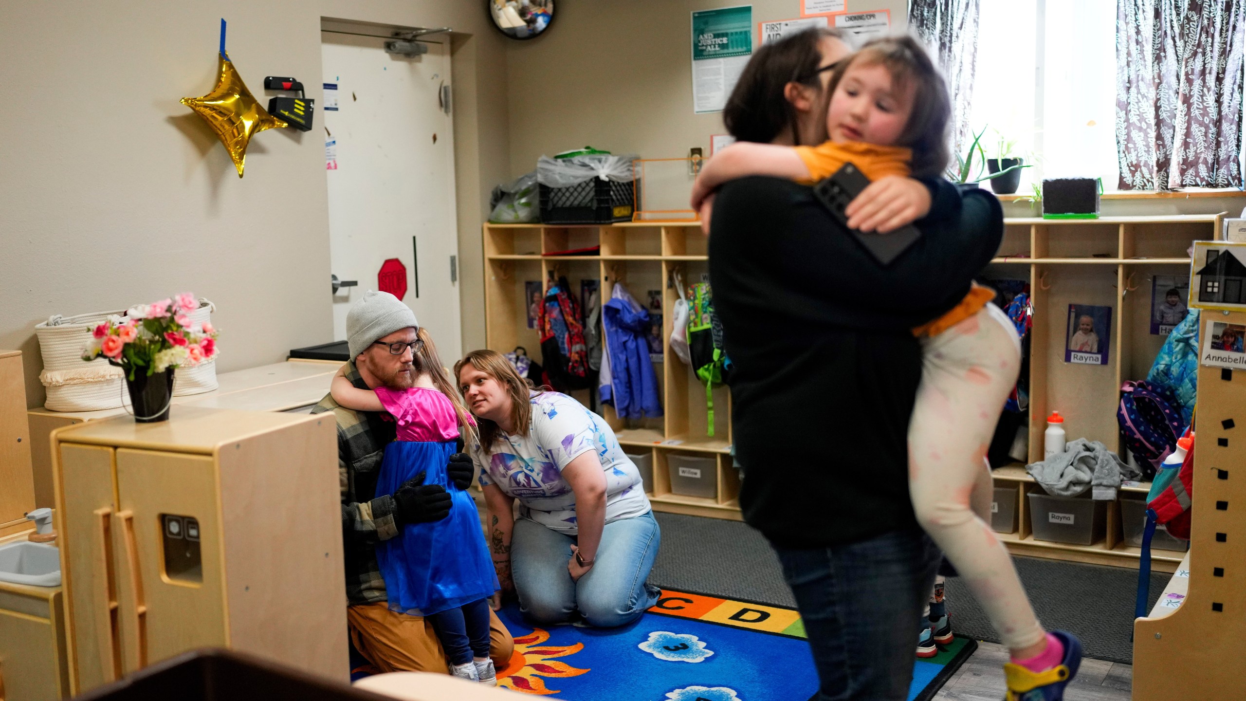 FILE - Olivia Starr clings to her father, Thaxter Hall, as Associate Educator Jessica Clark works to comfort her as she is dropped off for the last day of school at the Meadow Lakes CCS Early Learning, a Head Start center, May 8, 2024, in Wasilla, Alaska. (AP Photo/Lindsey Wasson, File)