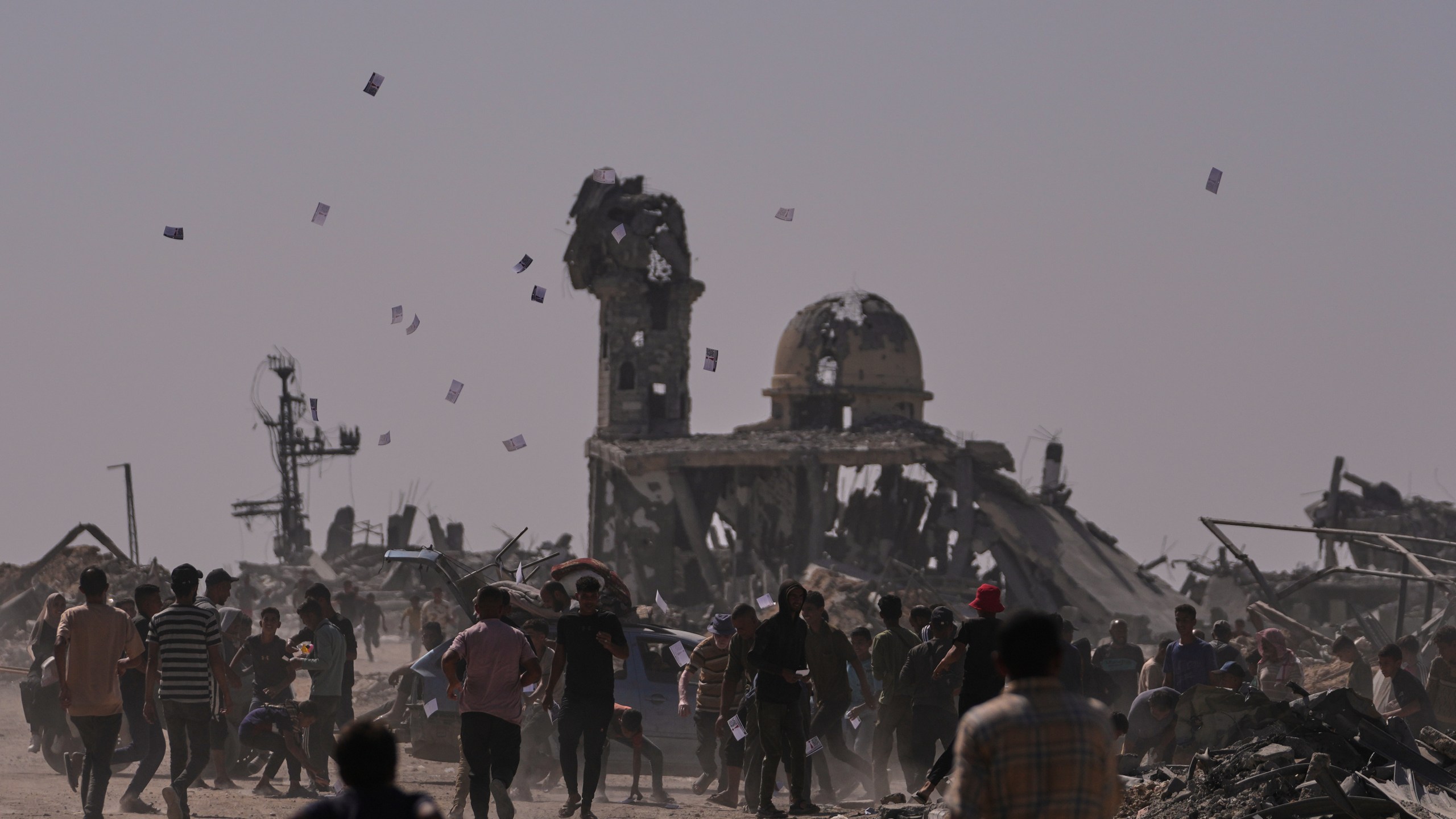 Palestinians collect leaflets dropped by an Israeli drone warning people to stay away from the so-called yellow line in Khan Younis, in the southern Gaza Strip, Monday, Oct. 20, 2025. (AP Photo/Jehad Alshrafi)