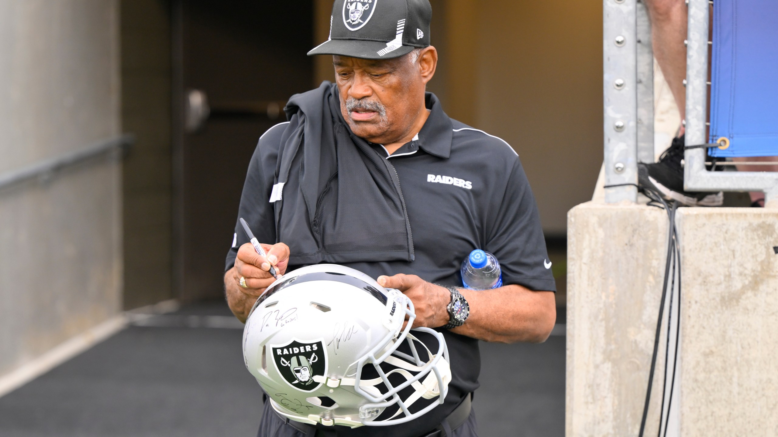 FILE - Former Oakland Raiders safety George Atkinson signs his autograph before the NFL football exhibition Hall of Fame Game between the Las Vegas Raiders and the Jacksonville Jaguars, Aug. 4, 2022, in Canton, Ohio. (AP Photo/David Richard, file)