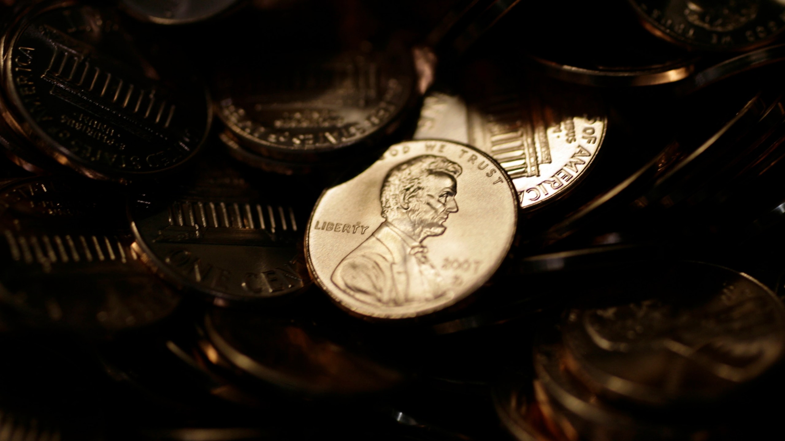 FILE - A lone penny is illuminated in a bin of completed pennies at the U.S. Mint in Denver on Aug. 15, 2007. (AP Photo/David Zalubowski, File)