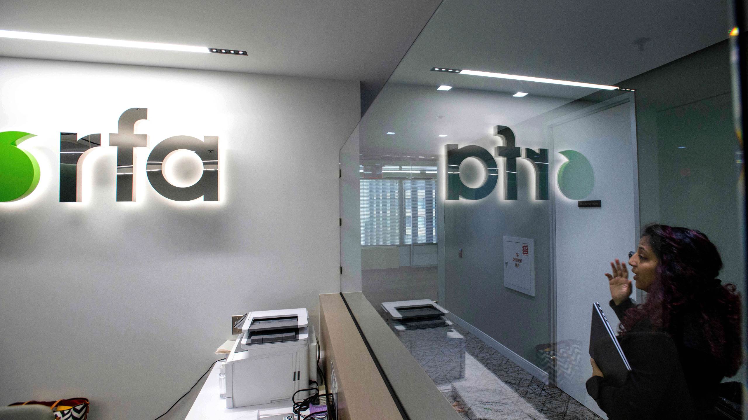 FILE - A woman walks past the empty receptionist desk at Radio Free Asia, April 1, 2025, in Washington. (AP Photo/Rod Lamkey, Jr., File)