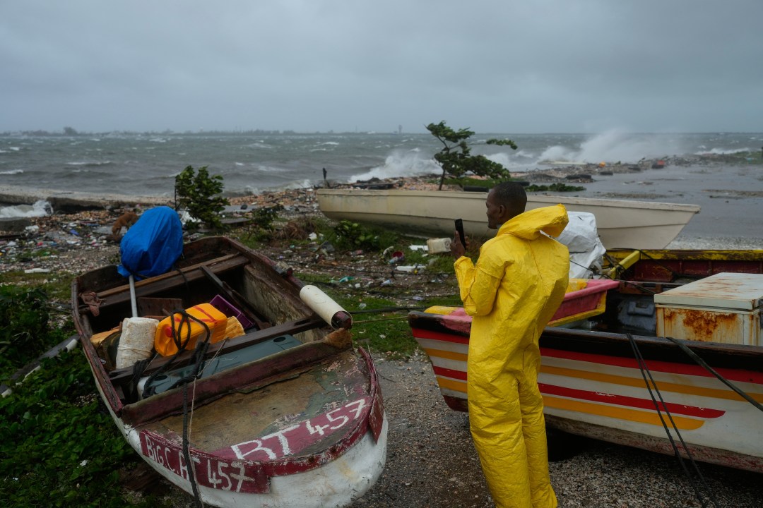 A man in a yellow rain jacket watching the coastline in Jamaica