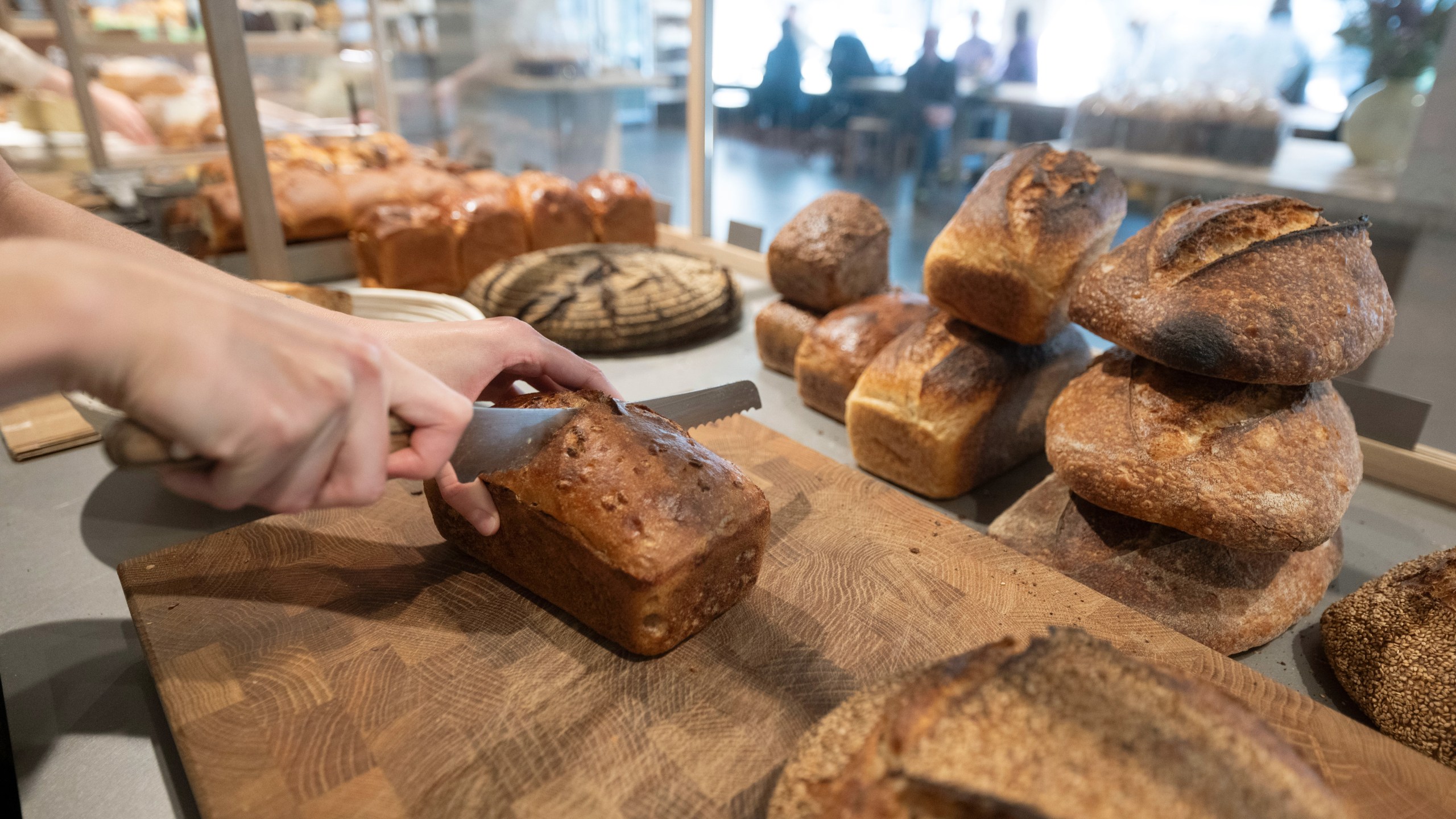 An employee of the Brotique sourdough bakery cuts a loaf of sourdough bread on the sales counter