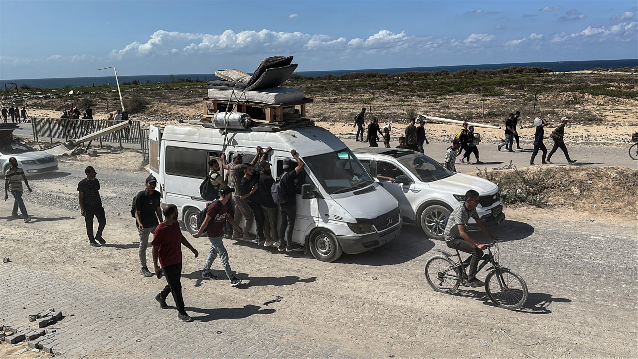 people surround vehicles and bicycles going down a road