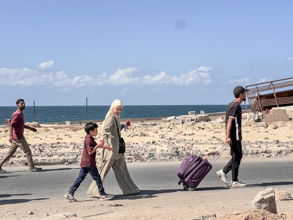 people walk down the road carrying luggage