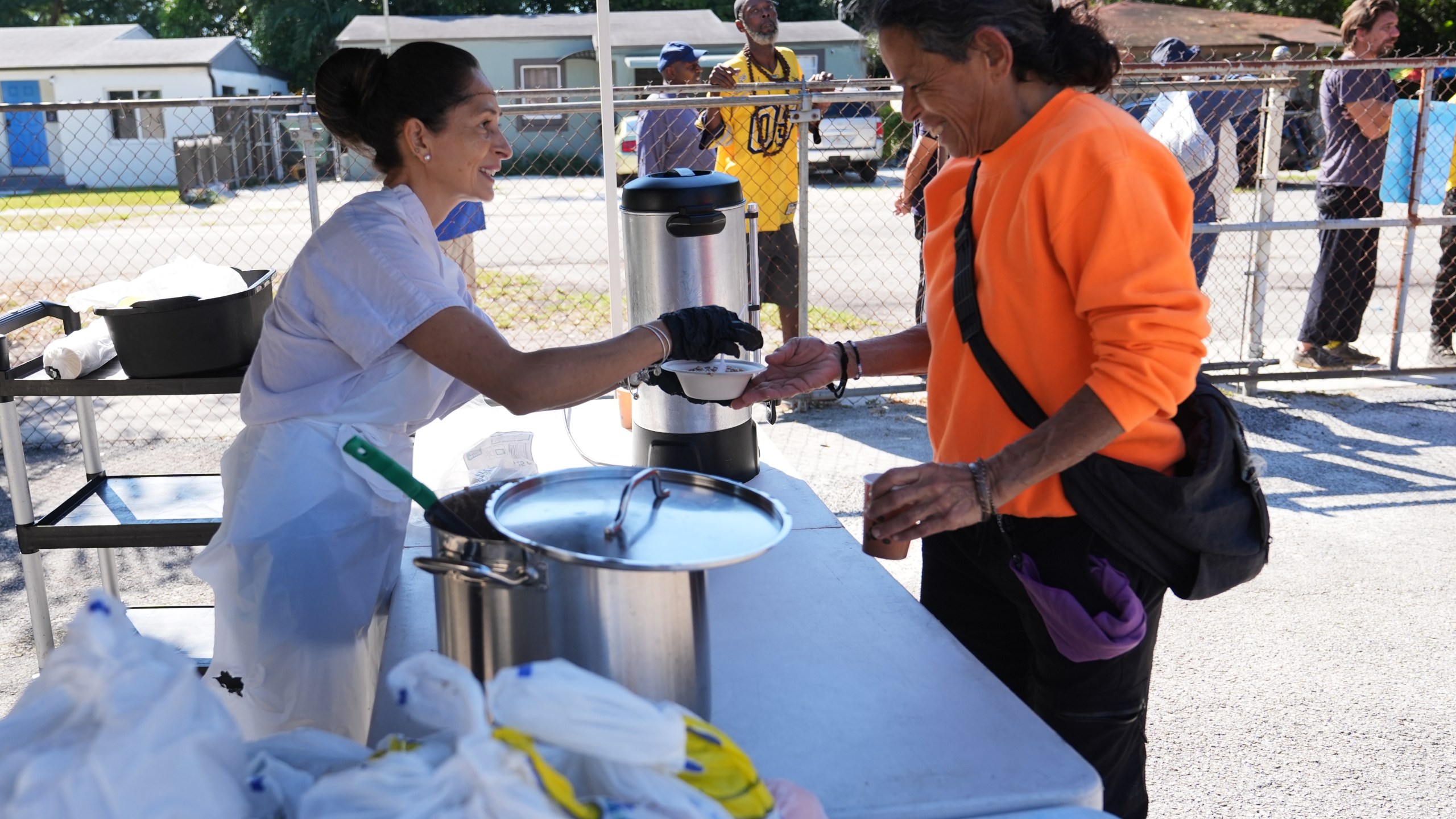 Volunteer Blanca Flores, left, passes out hot coffee, oatmeal and bags of food at a food distribution held by the Village (FREE)DGE at the Freedom Lab, Monday, Nov. 3, 2025, in Miami. (AP Photo/Lynne Sladky)