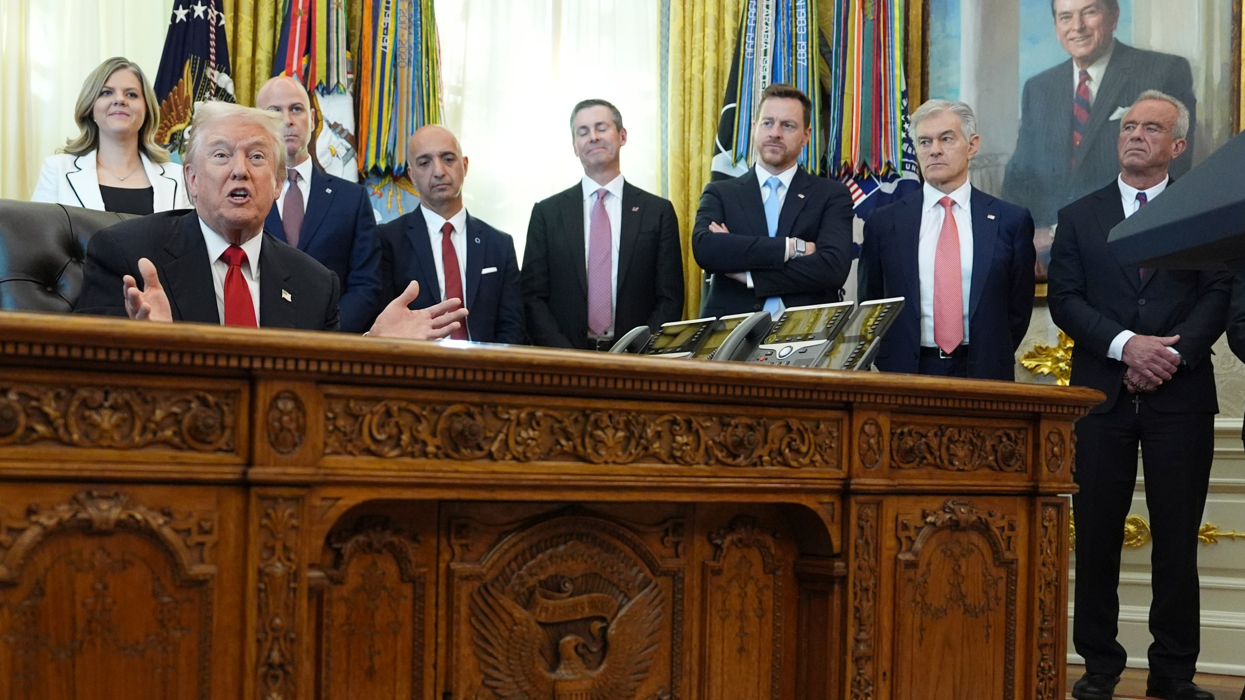 President Donald Trump speaks as Heidi Overton, deputy director of the White House Domestic Policy Council, from left, David Moore, president of Novo Nordisk Inc., Novo Nordisk President and CEO Mike Doustdar, Eli Lilly CEO David Ricks, Chris Klomp, director of the Centers for Medicare and Medicaid Services, Mehmet Oz, administrator of the Centers for Medicare & Medicaid Services, and Health and Human Services Secretary Robert F. Kennedy Jr. listen during an event about drug prices, Thursday, Nov. 6, 2025, in the Oval Office of the White House in Washington. (AP Photo/Evan Vucci)