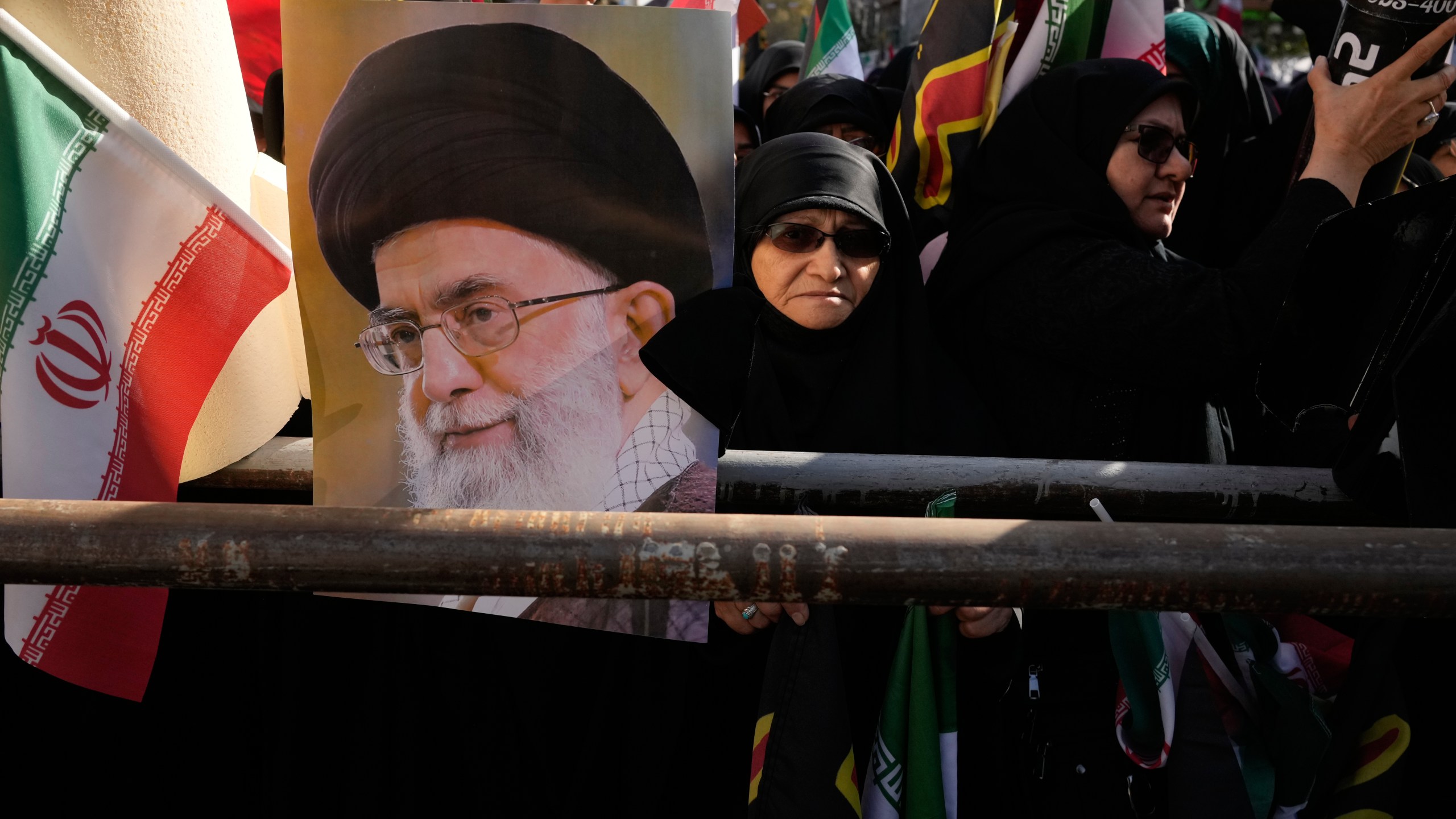 Demonstrators hold a poster of the Iranian Supreme Leader Ayatollah Ali Khamenei and an Iranian flag during an annual rally in front of the former U.S. Embassy in Tehran, celebrating the anniversary of the 1979 takeover of the embassy, Iran, Tuesday, Nov. 4, 2025. (AP Photo/Vahid Salemi)