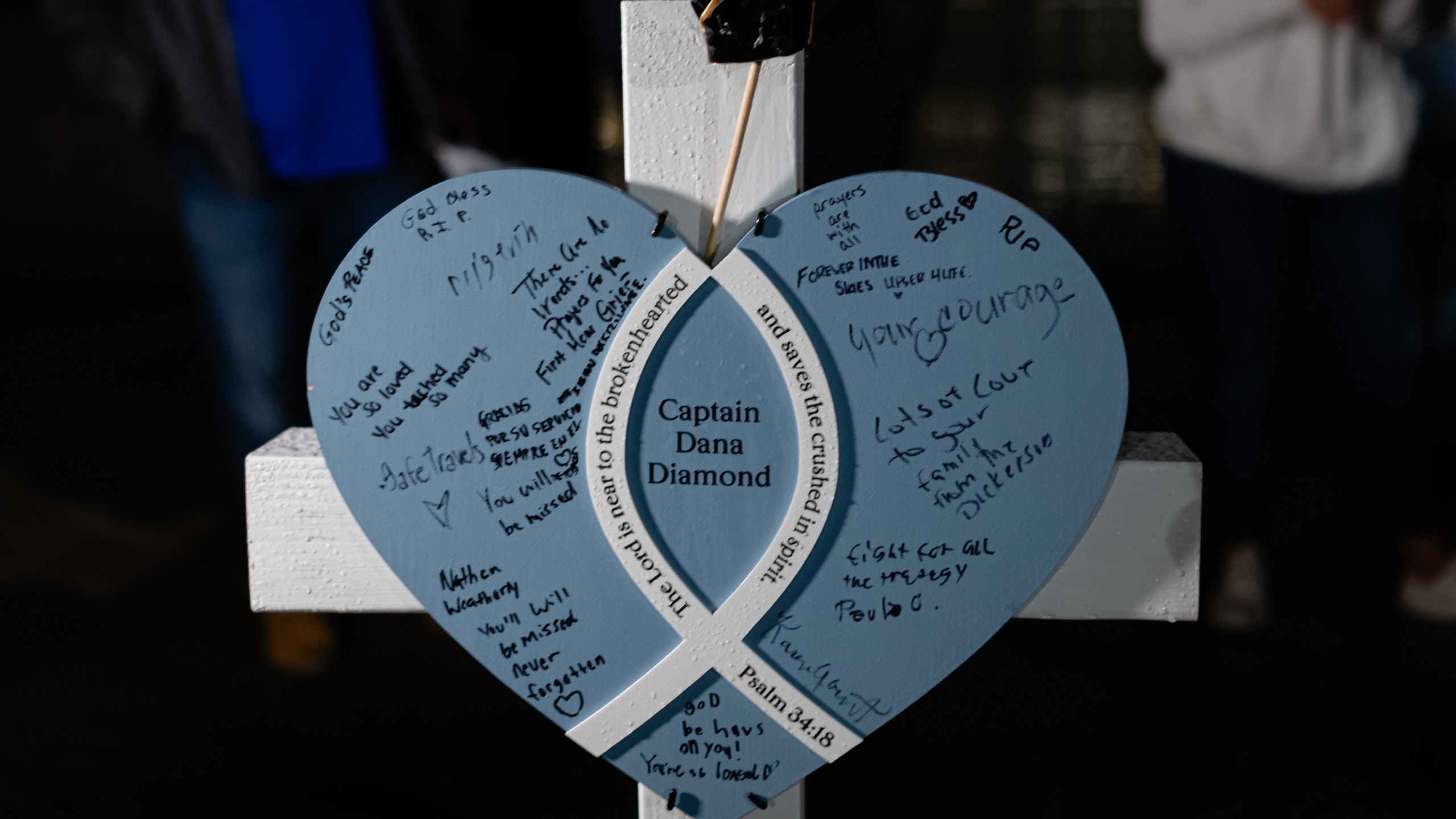 A placard and cross honoring Capt. Dana Diamond is seen during a vigil for those killed and missing after a UPS plane crashed, at the Great Lawn, Friday, Nov. 7, 2025, in Louisville, Ky. (AP Photo/Jon Cherry)