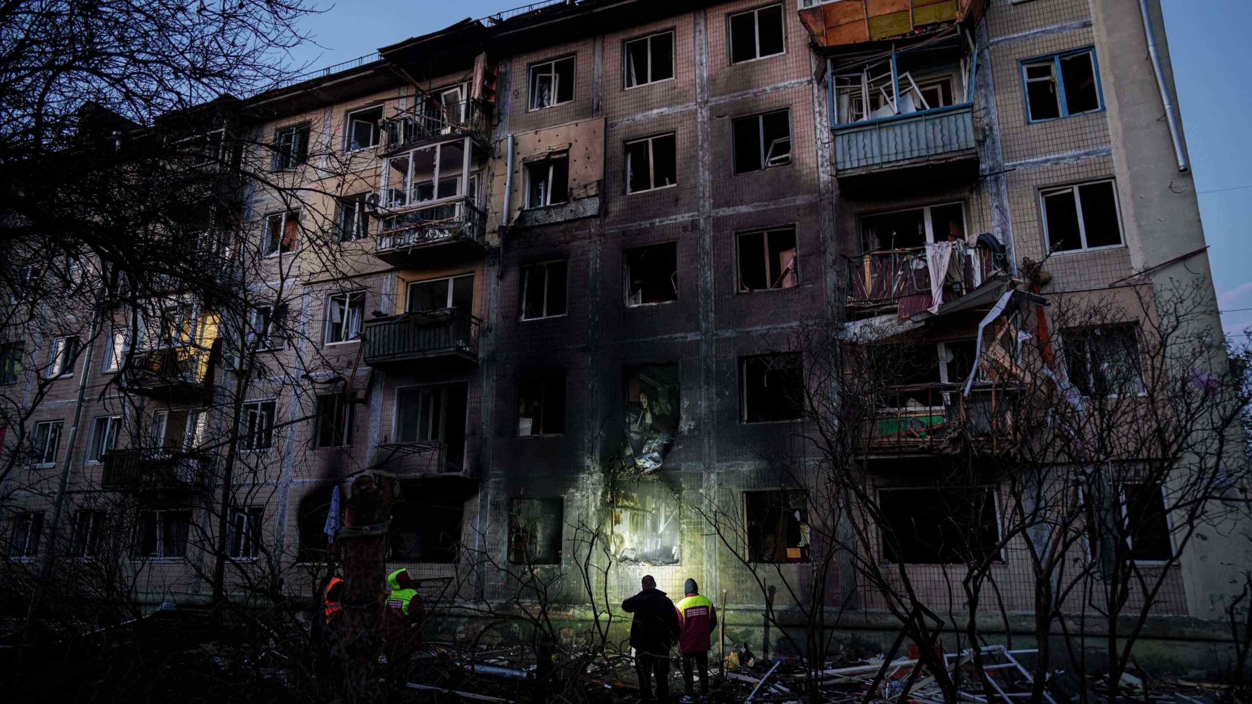 Municipal workers look at a residential building damaged after a Russian attack on Kyiv, Ukraine, on Friday, Nov. 14, 2025. (AP Photo/Evgeniy Maloletka)