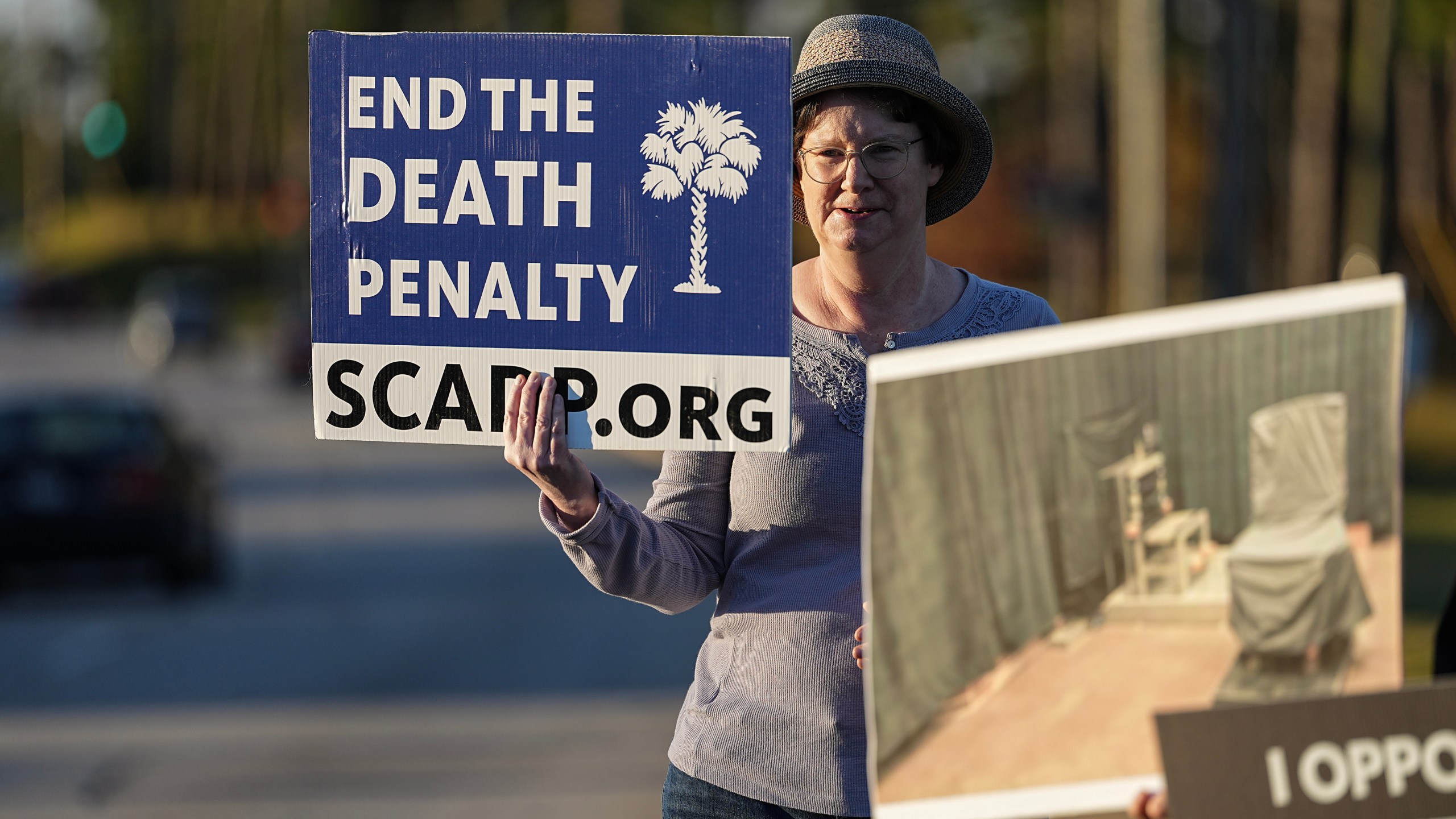 A protester holds signs outside of Broad River Correctional Institute prior to the scheduled execution of Stephen Bryant in Columbia, S.C., Friday, Nov. 14, 2025. (AP Photo/Matt Kelley)