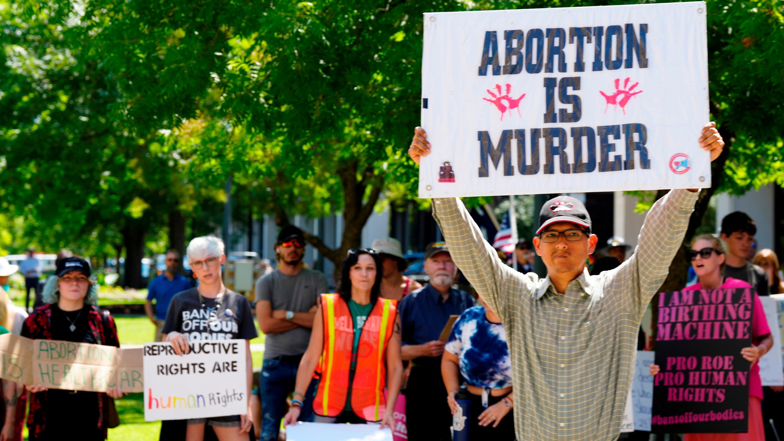 a man holding a sign reading ABORTION IS MURDER