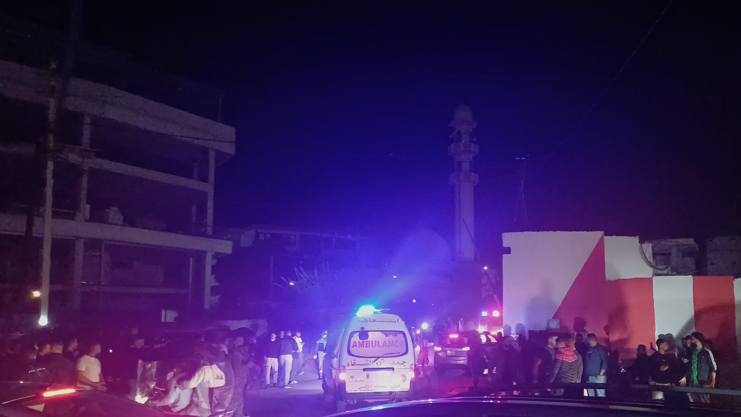 People gathering next of an ambulance as it enters the Ein el-Hilweh refugee camp in the southern port city of Sidon, Lebanon, Tuesday, Nov. 18, 2025. (AP Photo/Mohammed Zaatari)