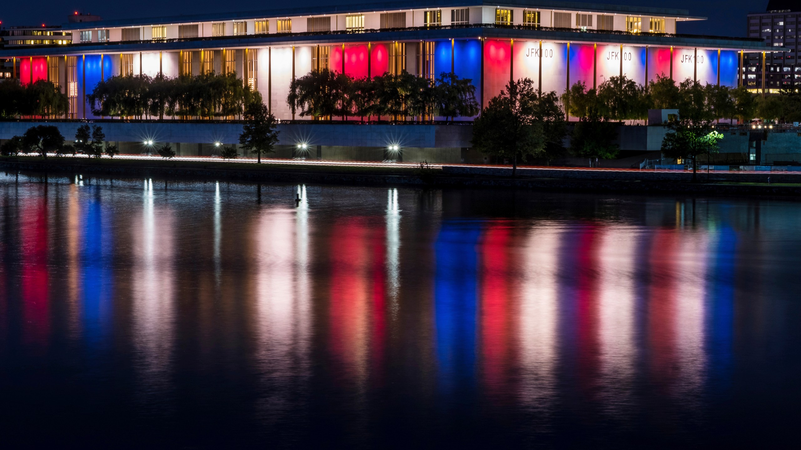 FILE - The red, white and blue lights, marking the 100th birthday of President John F. Kennedy, on the outside of the Kennedy Center for the Performing Arts are reflected in the Potomac River in Washington, May 26, 2017. AP Photo/J. David Ake, File)