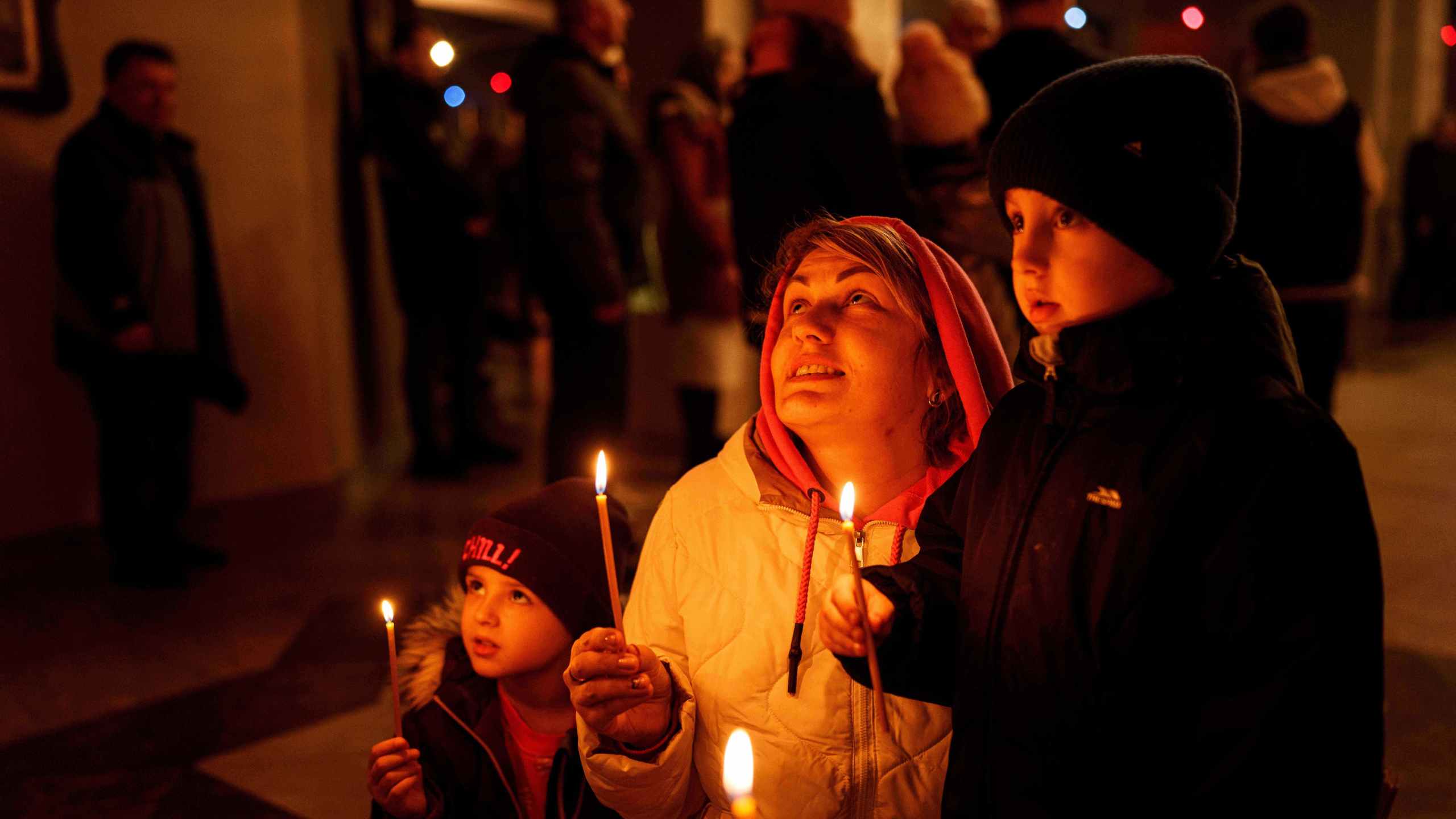 A mother with her children pray during service at the Holy Apostle Andrew church in Bucha, Ukraine, on Sunday, Nov. 23, 2025. (AP Photo/Evgeniy Maloletka)
