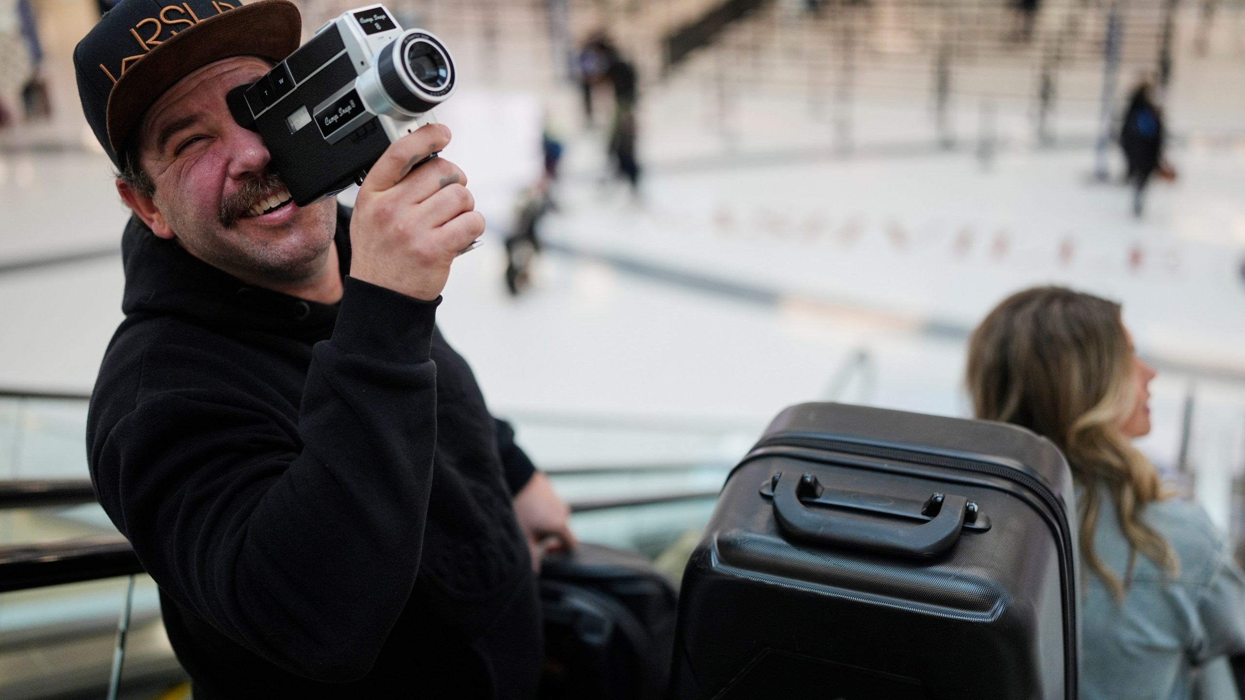 Jordan Heid uses an old film camera as he arrives for his flight at the Nashville International Airport, Tuesday, Nov. 25, 2025, in Nashville, Tenn. (AP Photo/George Walker IV)