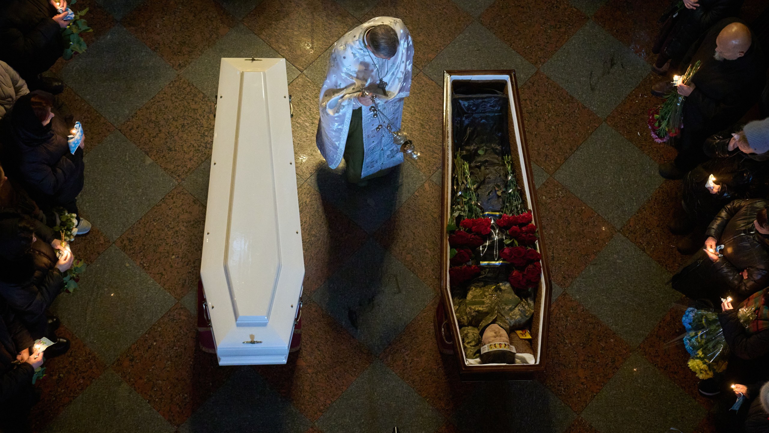 A priest conducts a service as people say the last goodbye to Ukrainian soldiers Myroslava Kopcha and Artur Vilchynski, who were killed in Russia-Ukraine war, during a funeral ceremony at St. Michael Cathedral in Kyiv, Ukraine, Friday, Nov. 28, 2025. (AP Photo/Efrem Lukatsky)