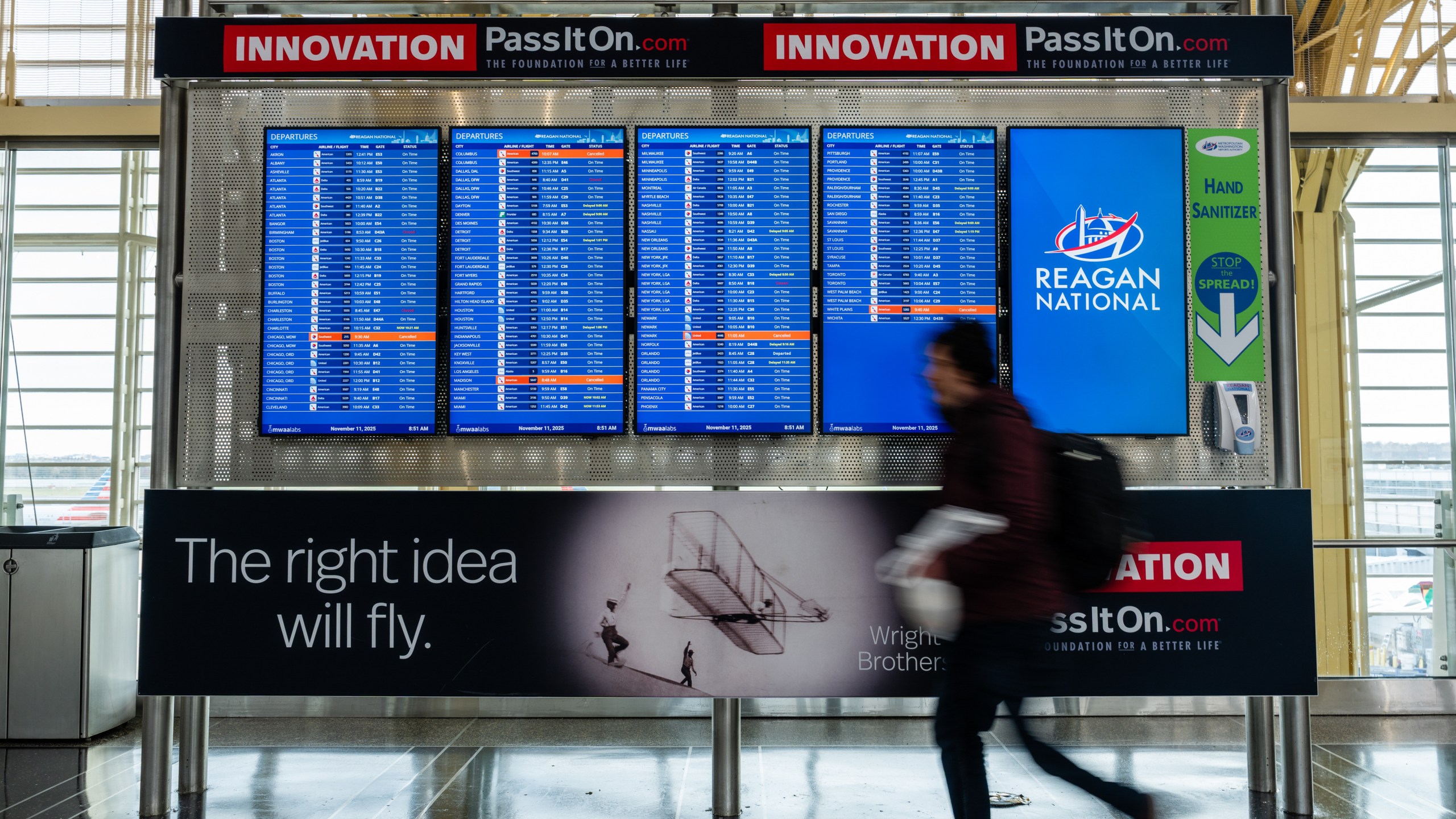 A traveler near a flight information board at Ronald Reagan Washington National Airport (DCA) in Arlington, Virginia, US, on Tuesday, Nov. 11, 2025. The havoc plaguing the US travel industry will likely escalate Tuesday when tighter federal restrictions on flights take effect, even while lawmakers move closer toward ending the government shutdown. Photographer: Eric Lee/Bloomberg via Getty Images